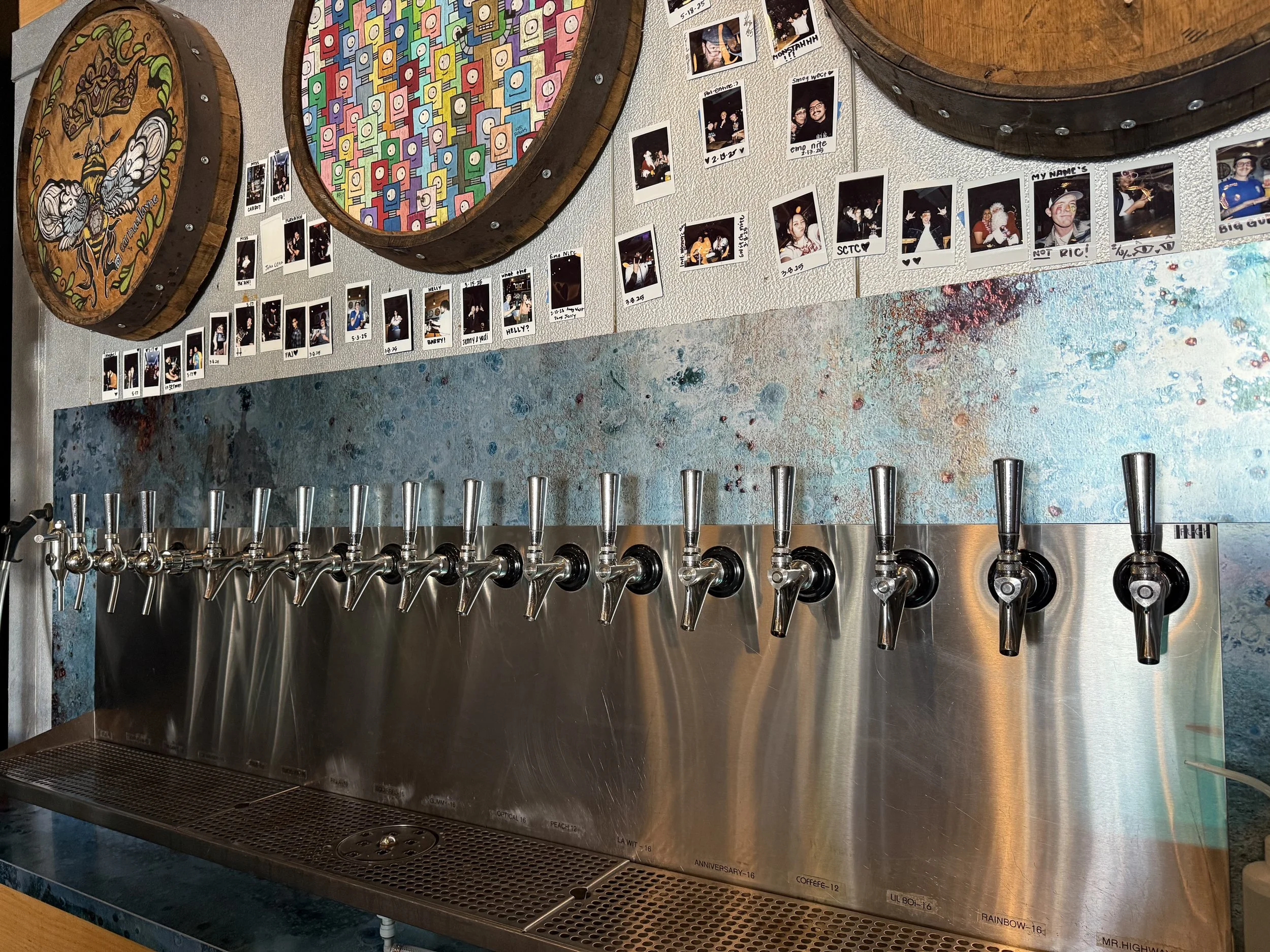 Detailed view of the tap handles at Smog City West along with barrel lid artwork hanging above them.
