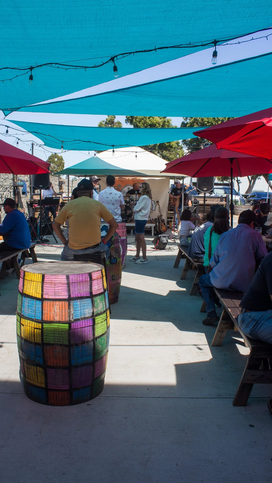Guests sitting under the covered patio outside Smog City Brewery and watching a live band perform.