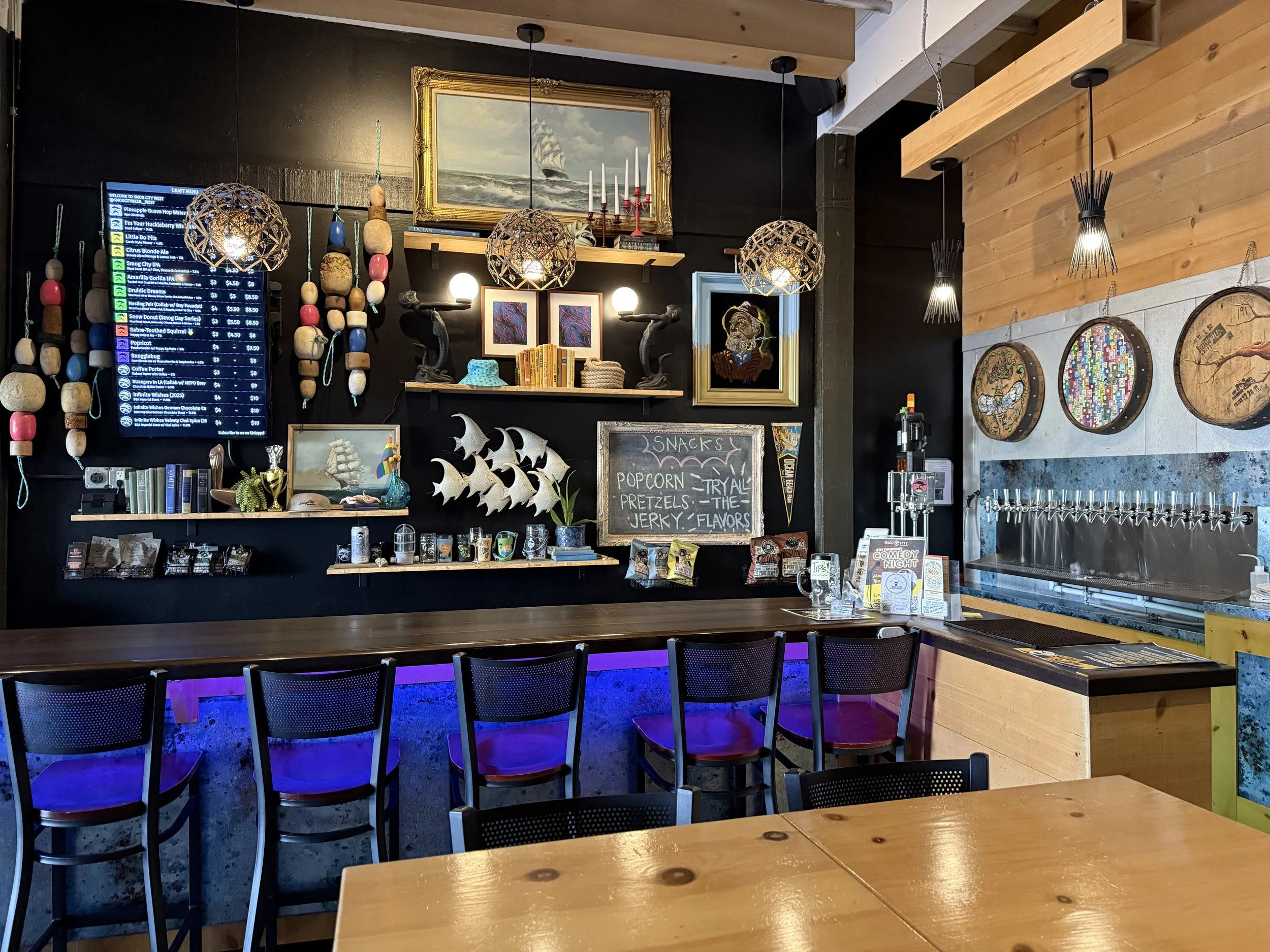 View of bar seating area in Smog City West with decorations on the wall and the digital menu above.