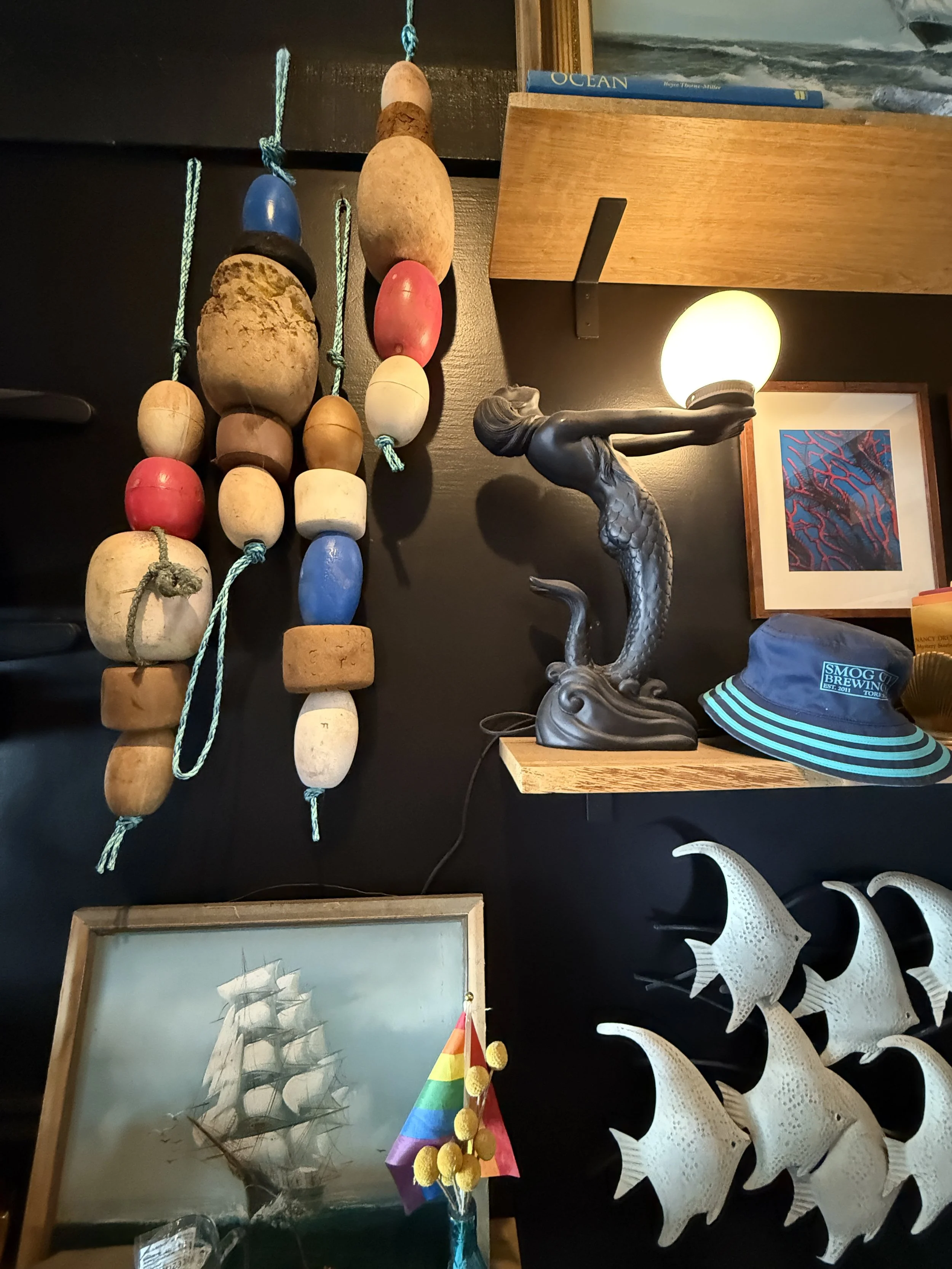 Close up of taproom decor including paintings of ships, hats, fish, and a lamp.