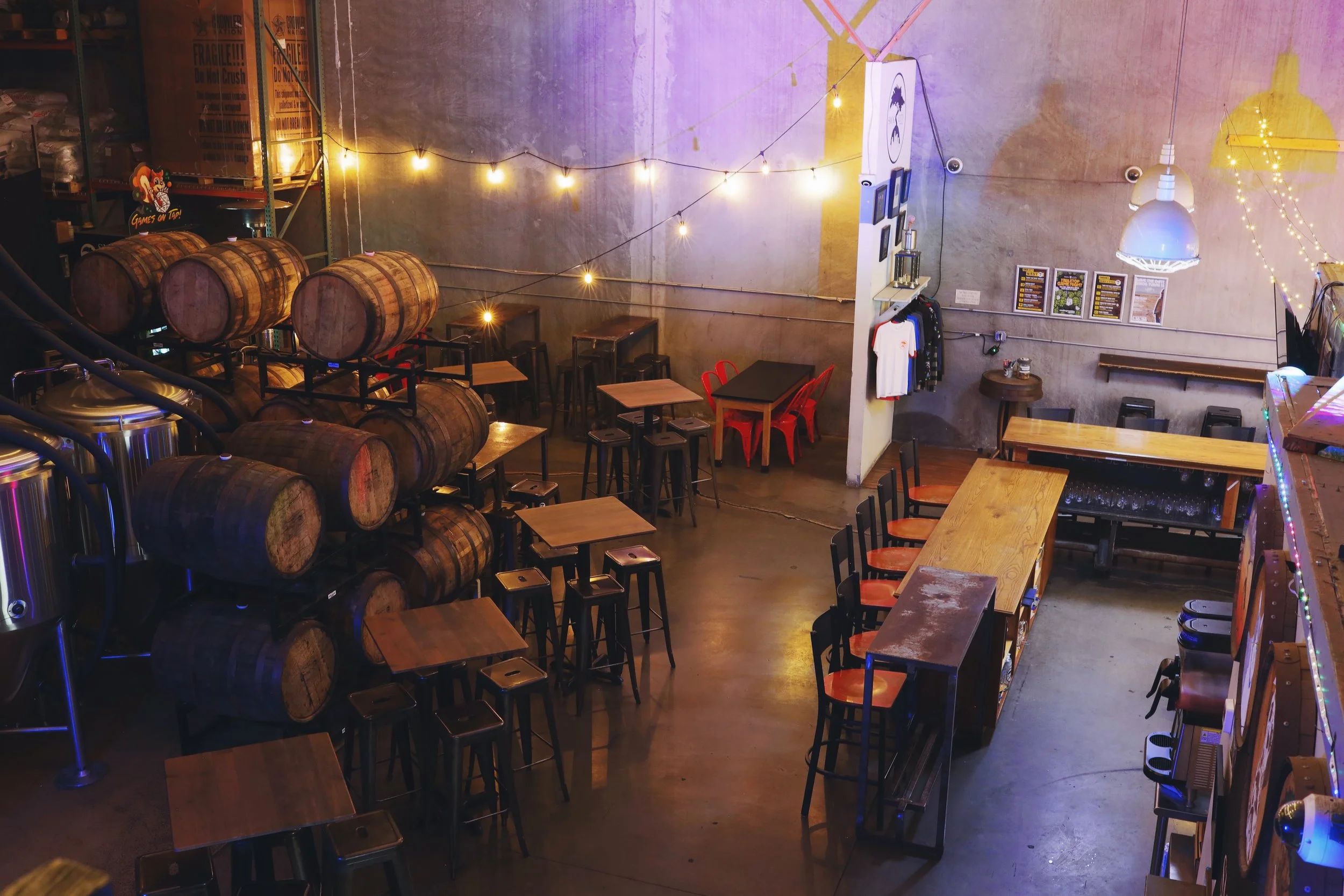 Overhead view of taproom floor with tables, chairs, and barrels.