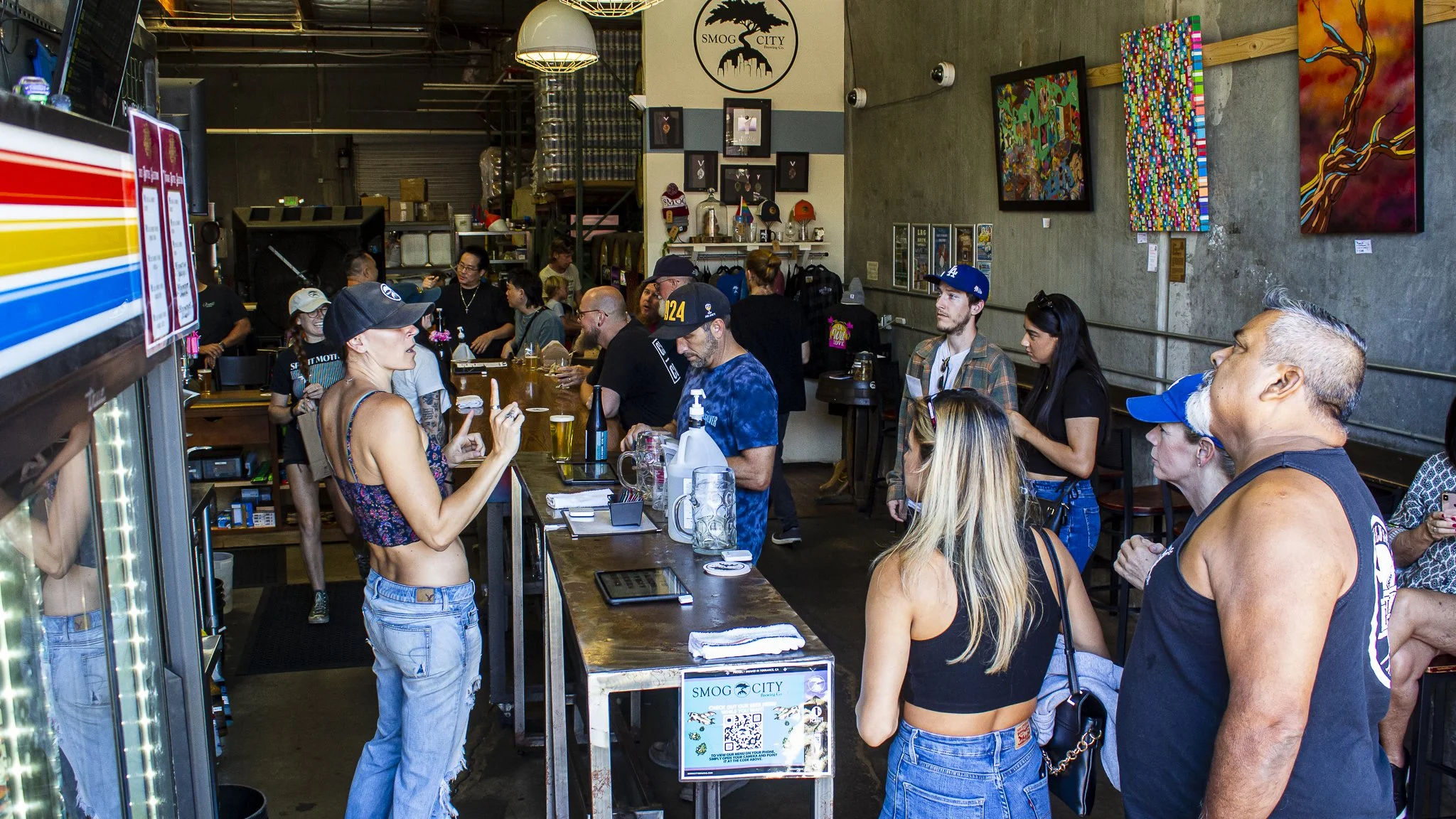 Customers standing inside Smog City Brewery at the counter and looking at the beer menu.