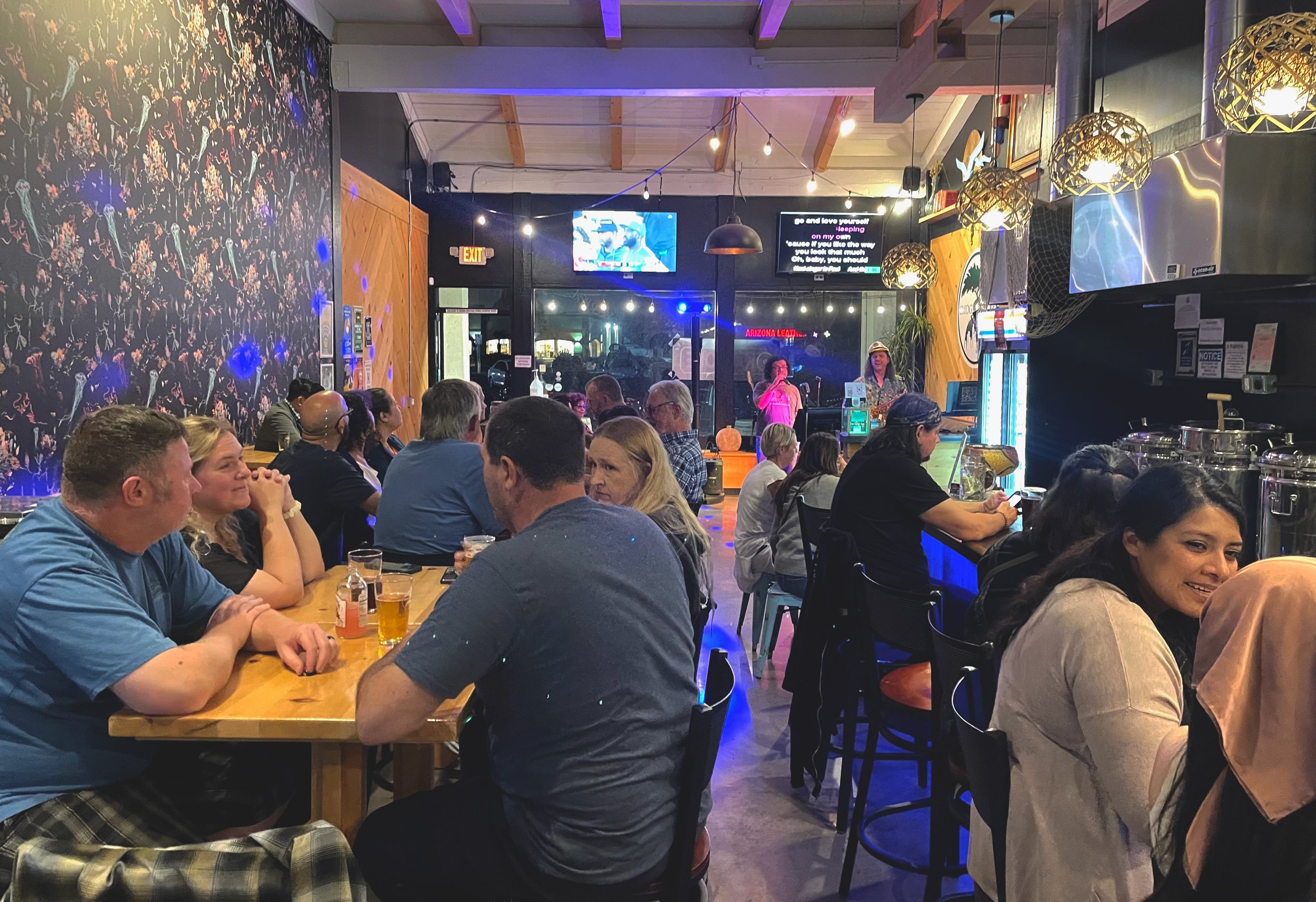 Large amount of guests sitting inside taproom during a karaoke performance.