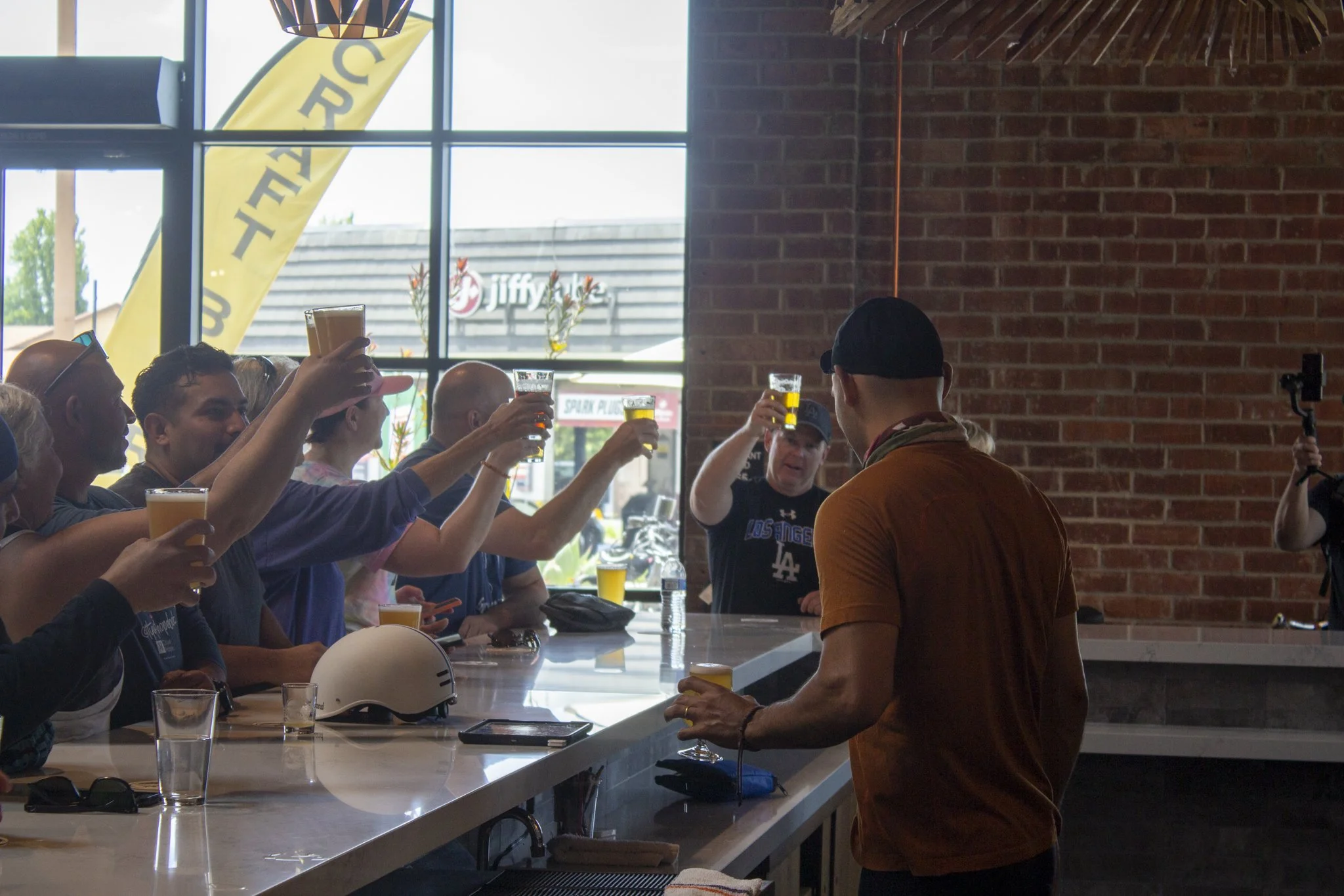 Group of customers all raising pint glasses to cheers each other at the same time.