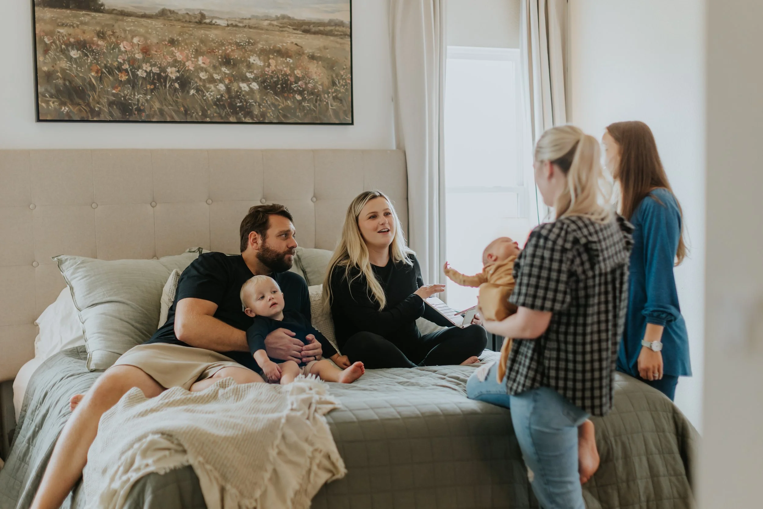 A family sits in their bed for a postpartum visit with their home birth midwife in Lubbock Texas.