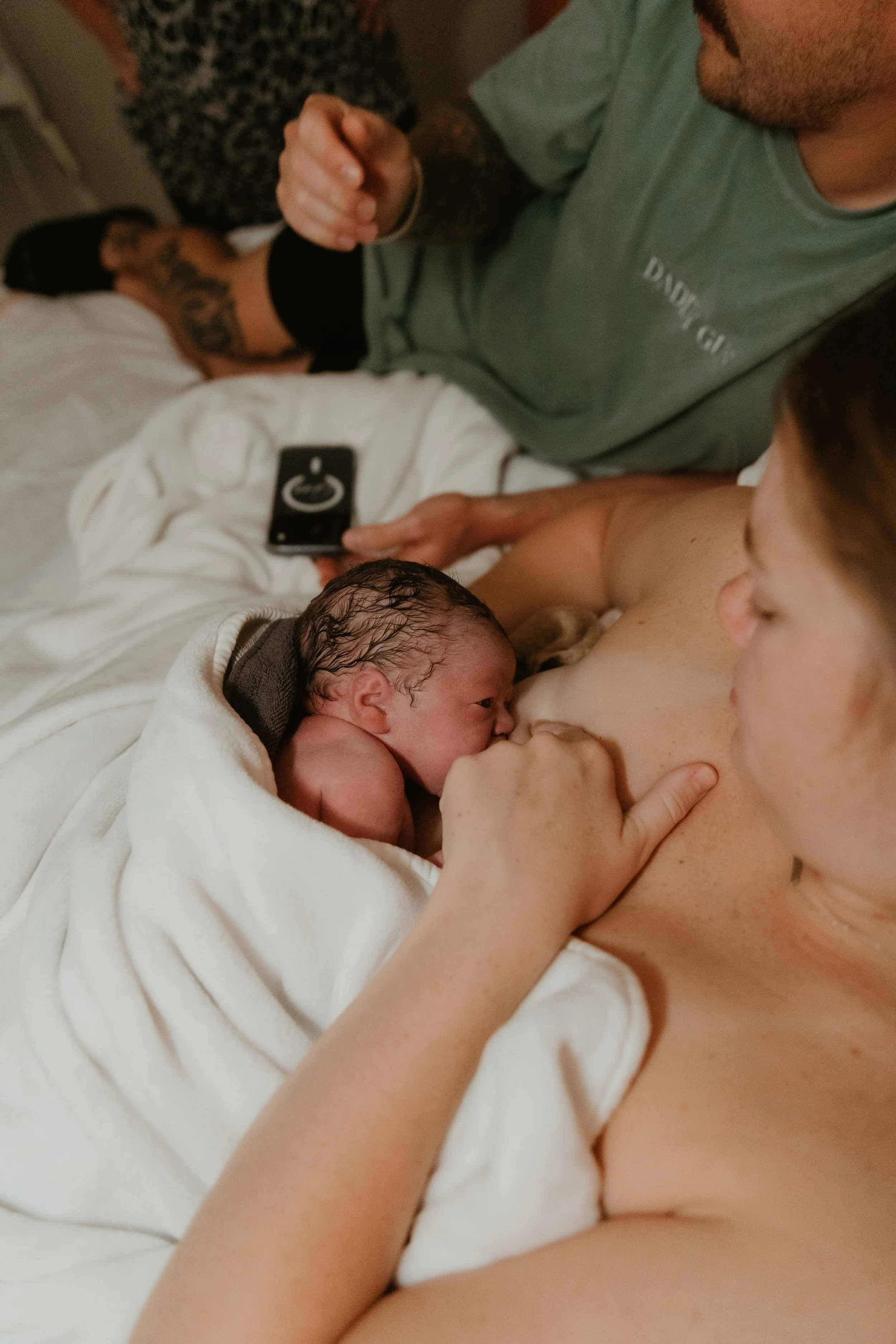 A mother nurses her newborn baby in bed following a home birth.