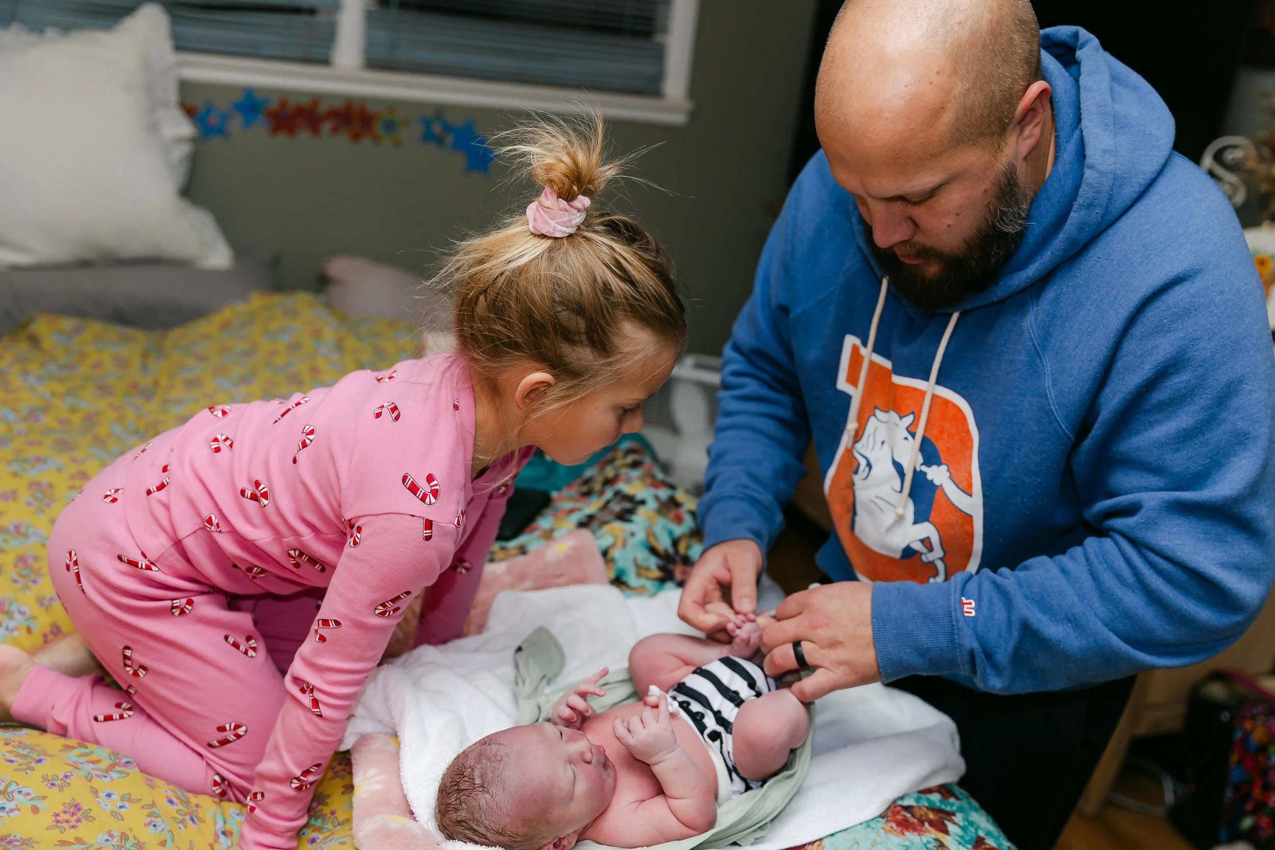 A big sister and father dress a newborn following their Lubbock Texas area home birth.