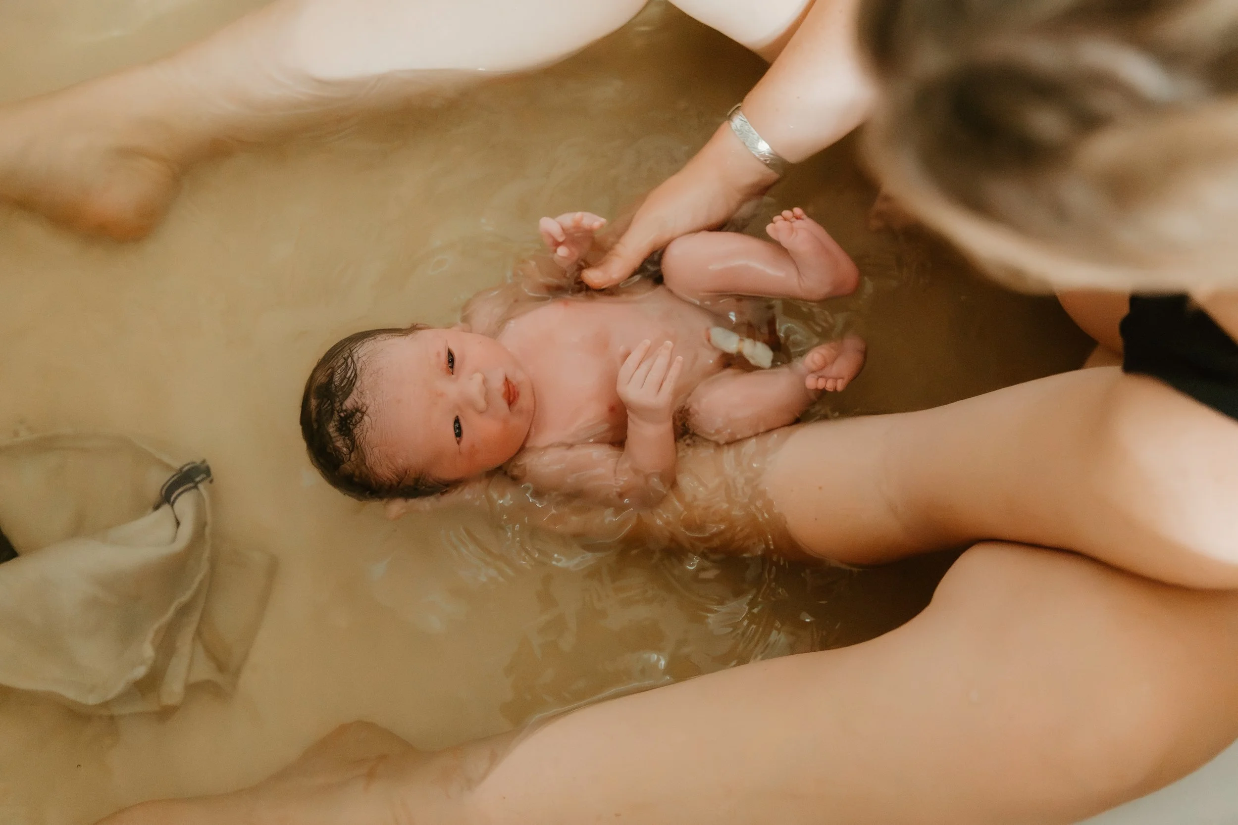 A mother cradles her newborn in the birth tub moments after a water birth at home in Lubbock, Texas.