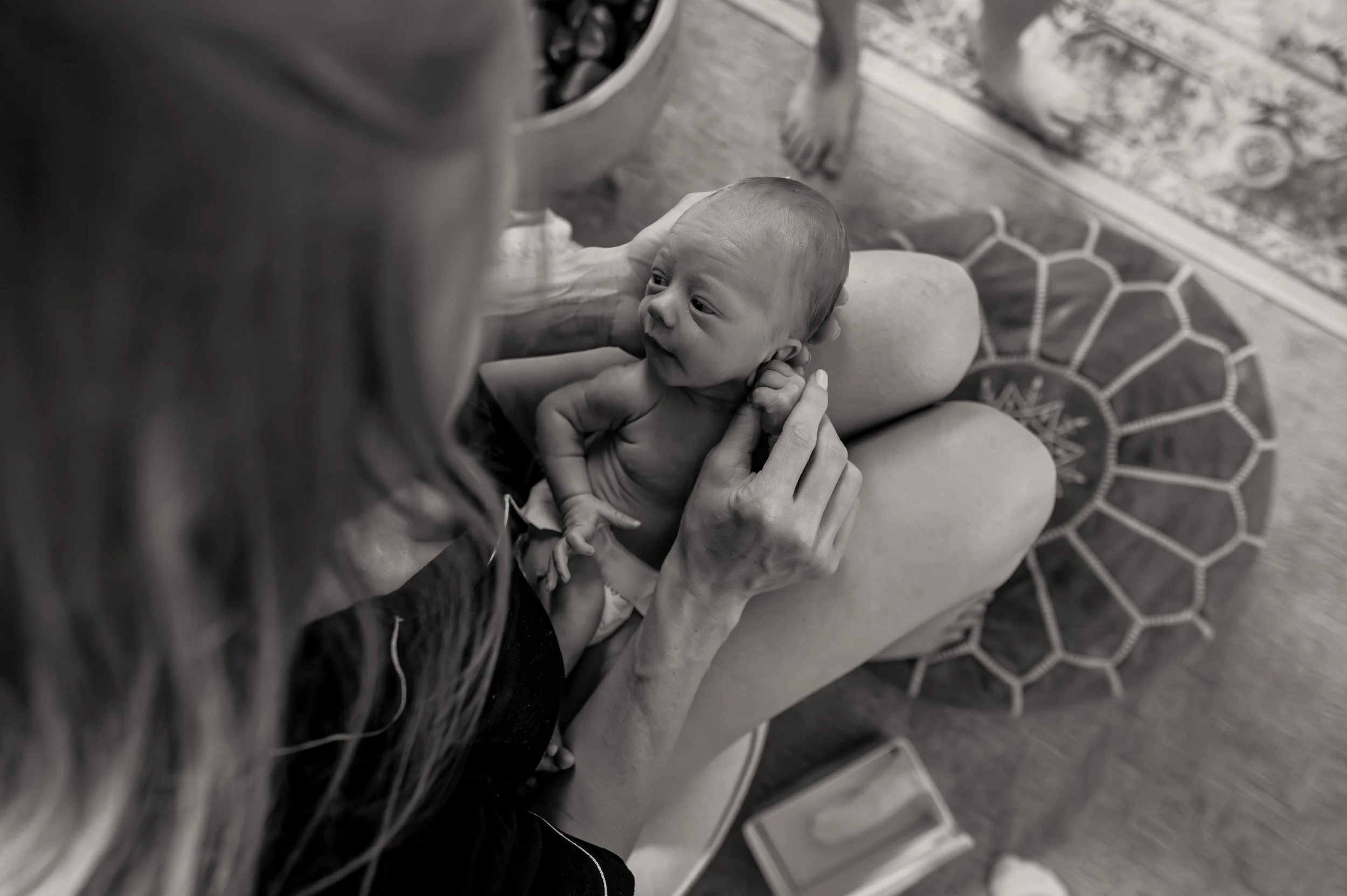 Newborn infant in diaper is held by his mother at an in home newborn midwife visit