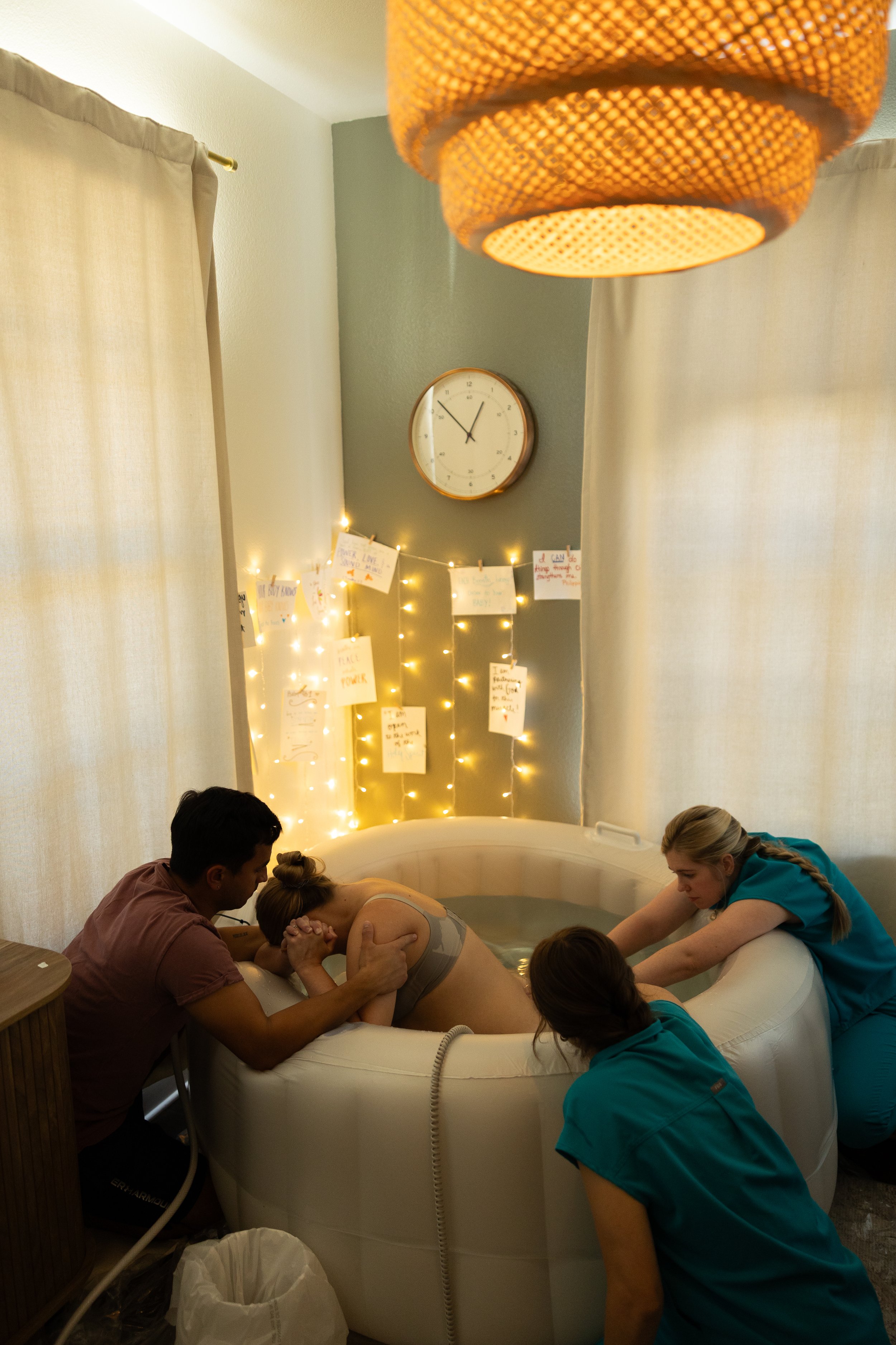 Midwives apply counter pressure to mother's back while she labors in inflatable birth tub.