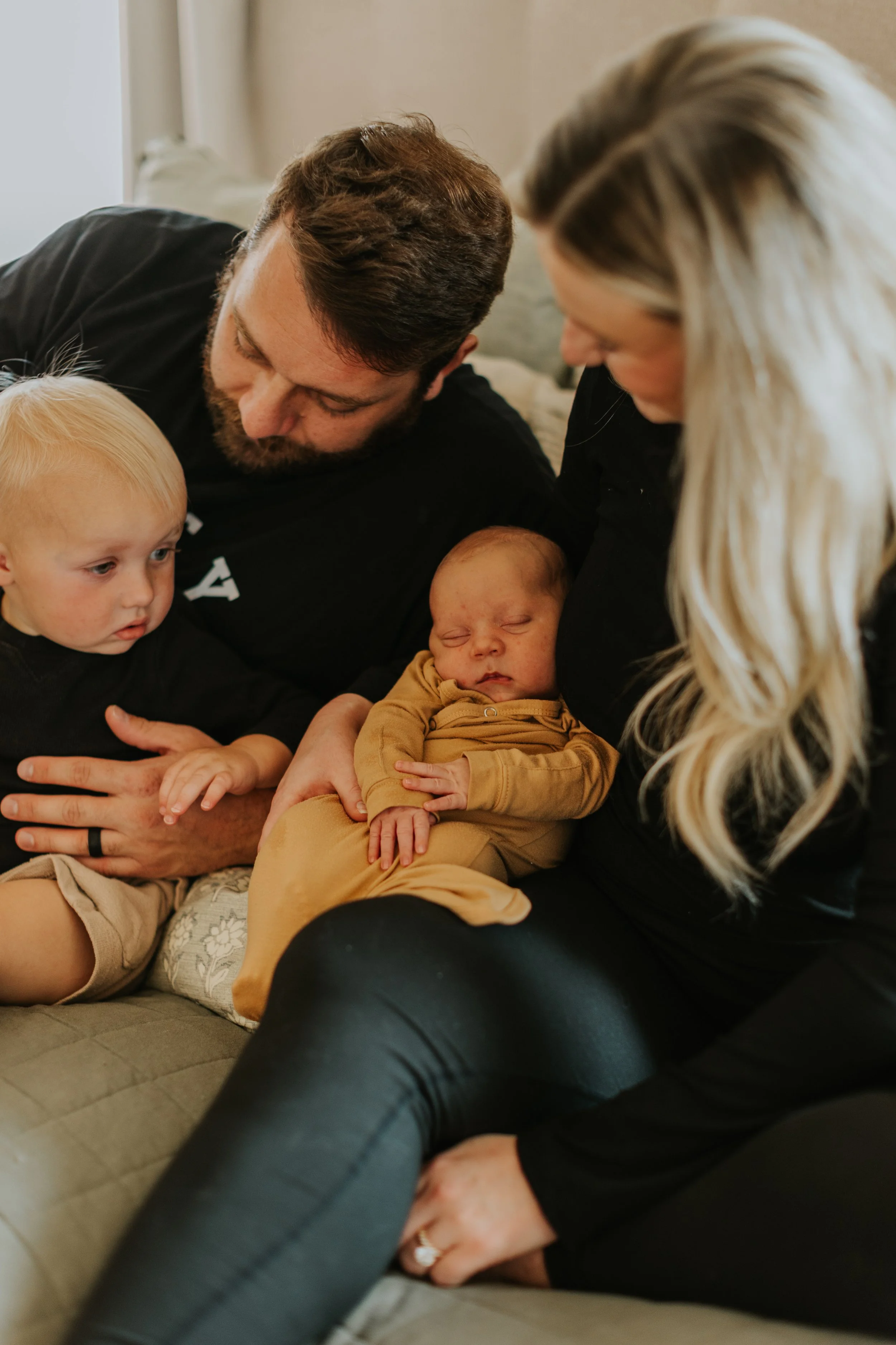 A Lubbock Texas family rest on a bed during a routine home based postpartum visit with their home birth midwife.