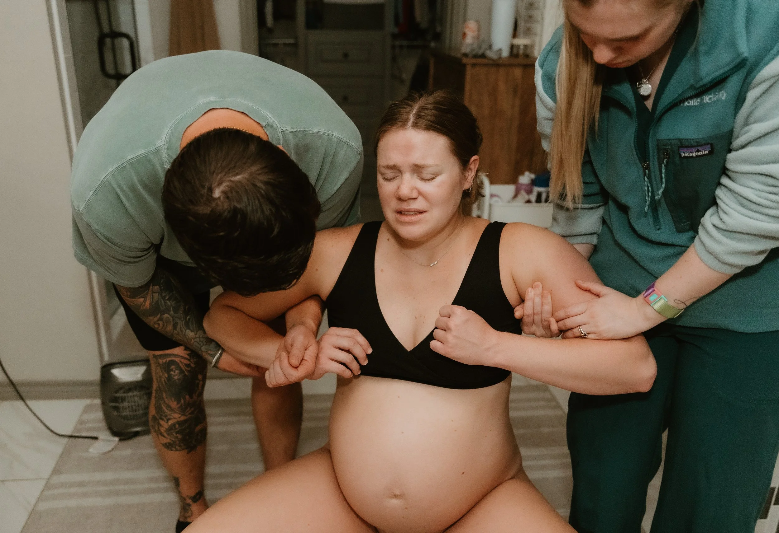 A woman is laboring at home with her husband and midwife at her side. 