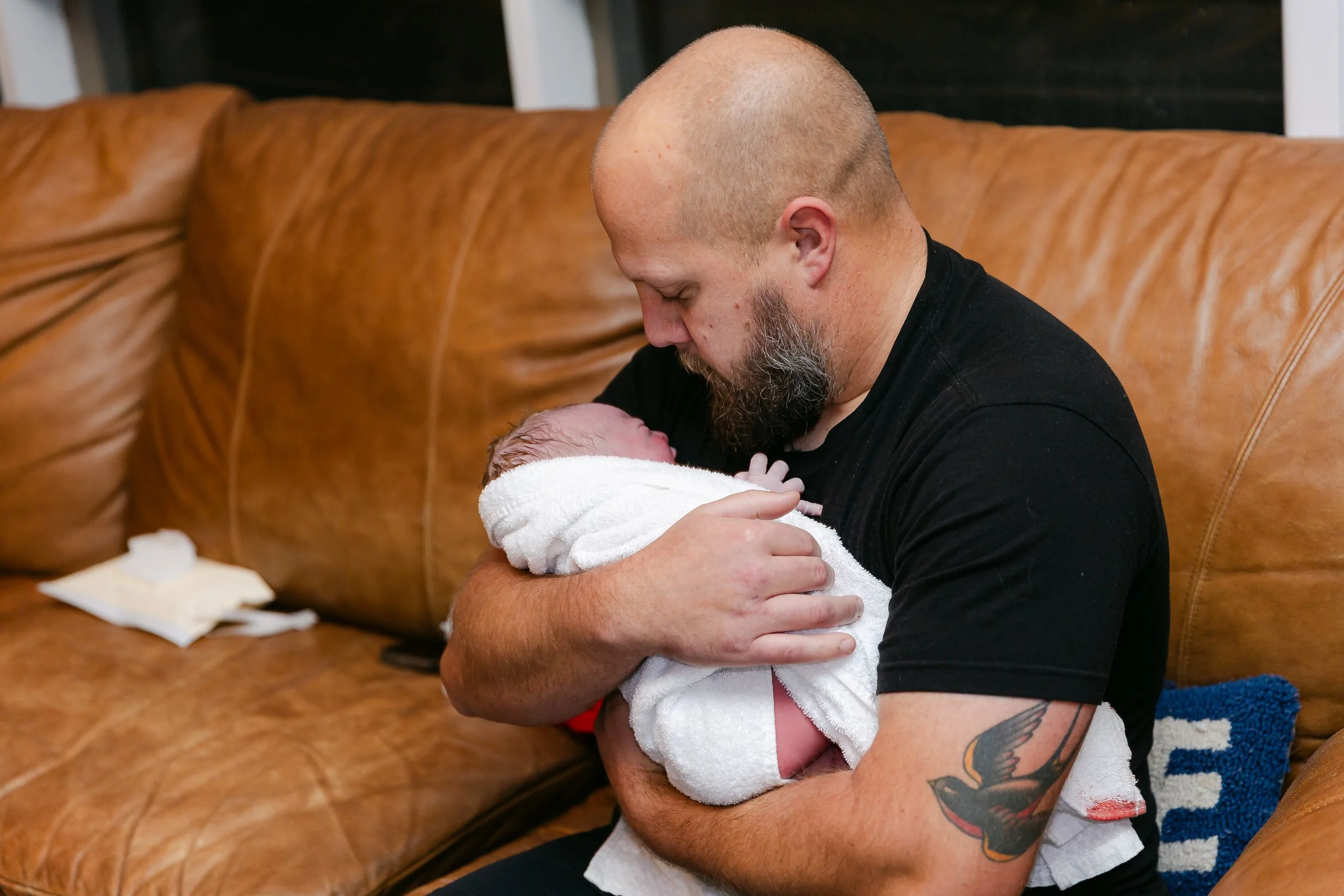 A father cradles his newborn in a towel following their Lubbock Texas area home birth.