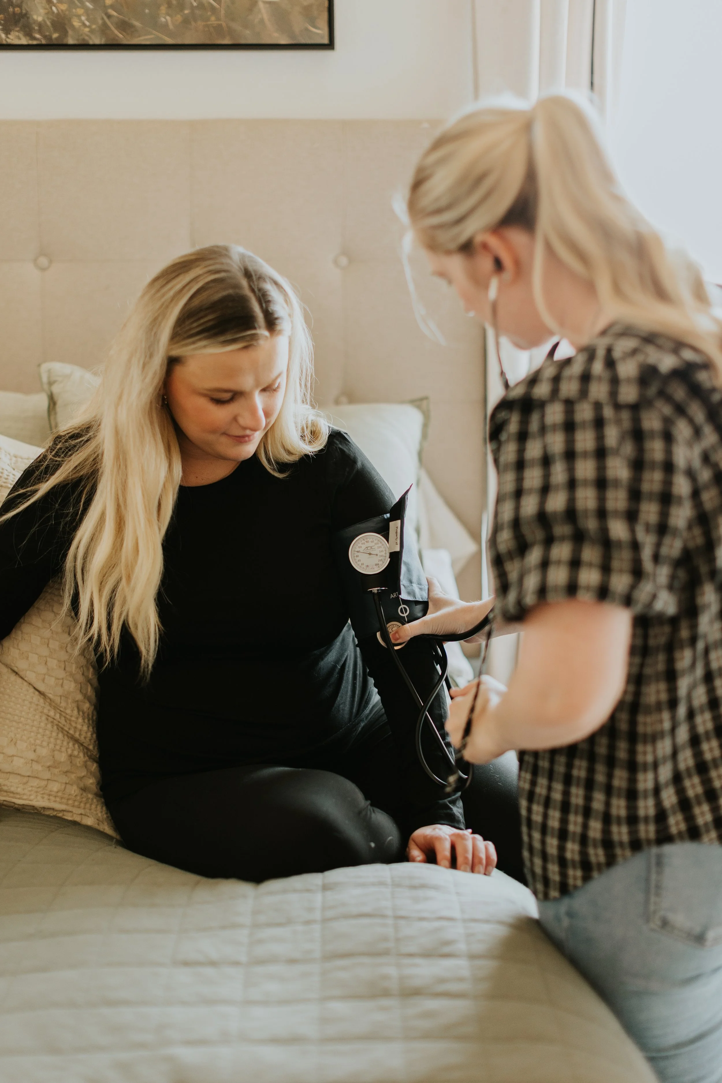Homebirth midwife takes postpartum mother's blood pressure during postpartum home visit.