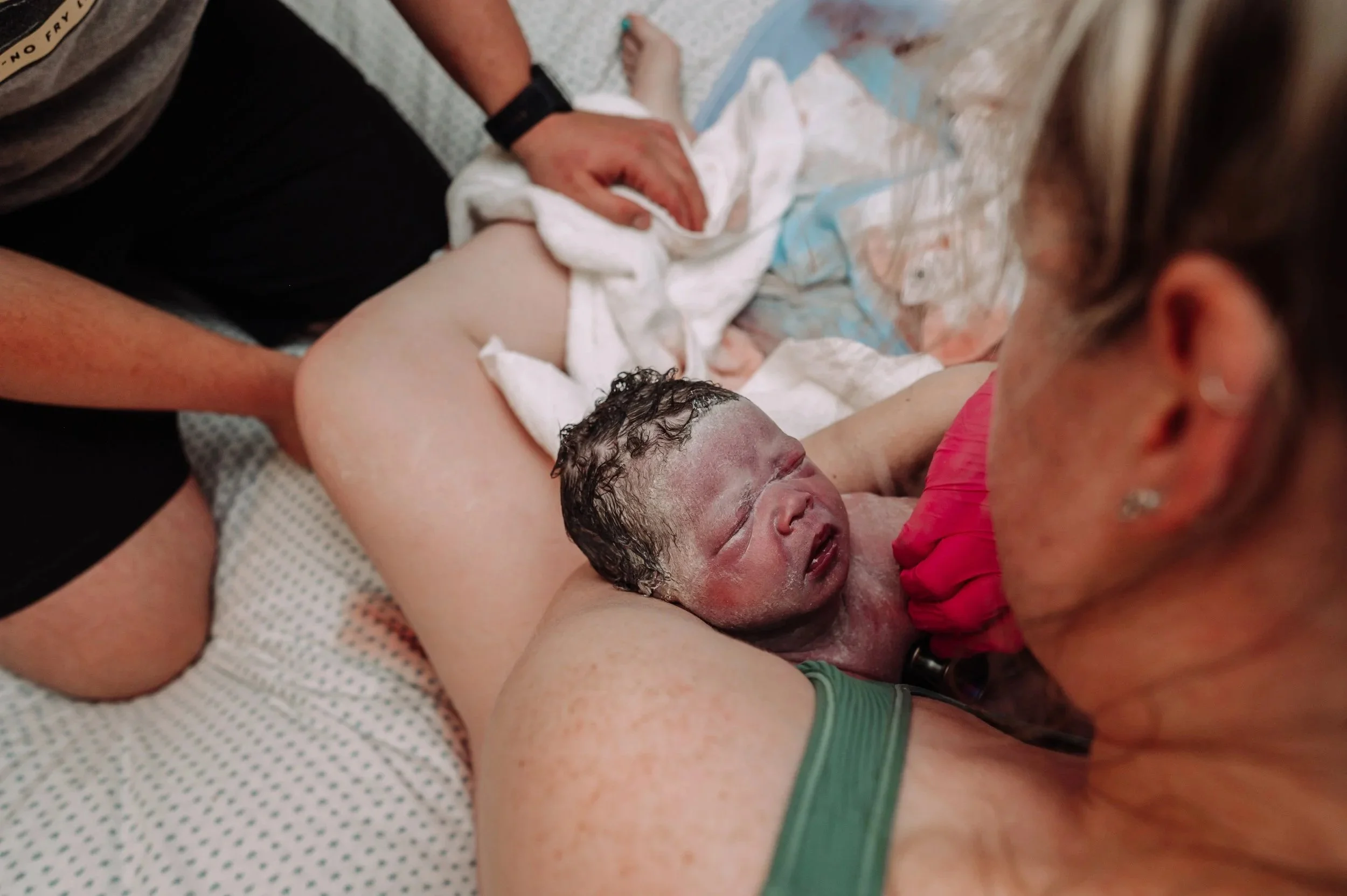 A midwife listens to a newborns heartbeat immediately following the birth while the baby is skin to skin with the mother.