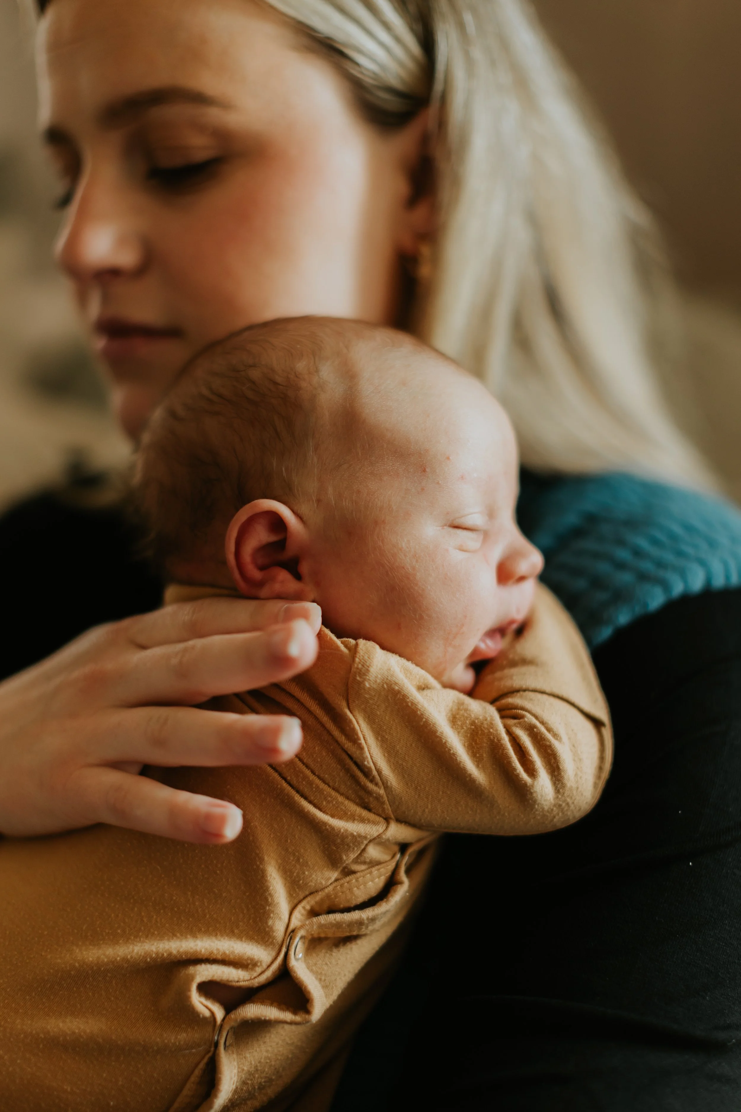 A mother holds her newborn during a routine home postpartum visit with her midwives.