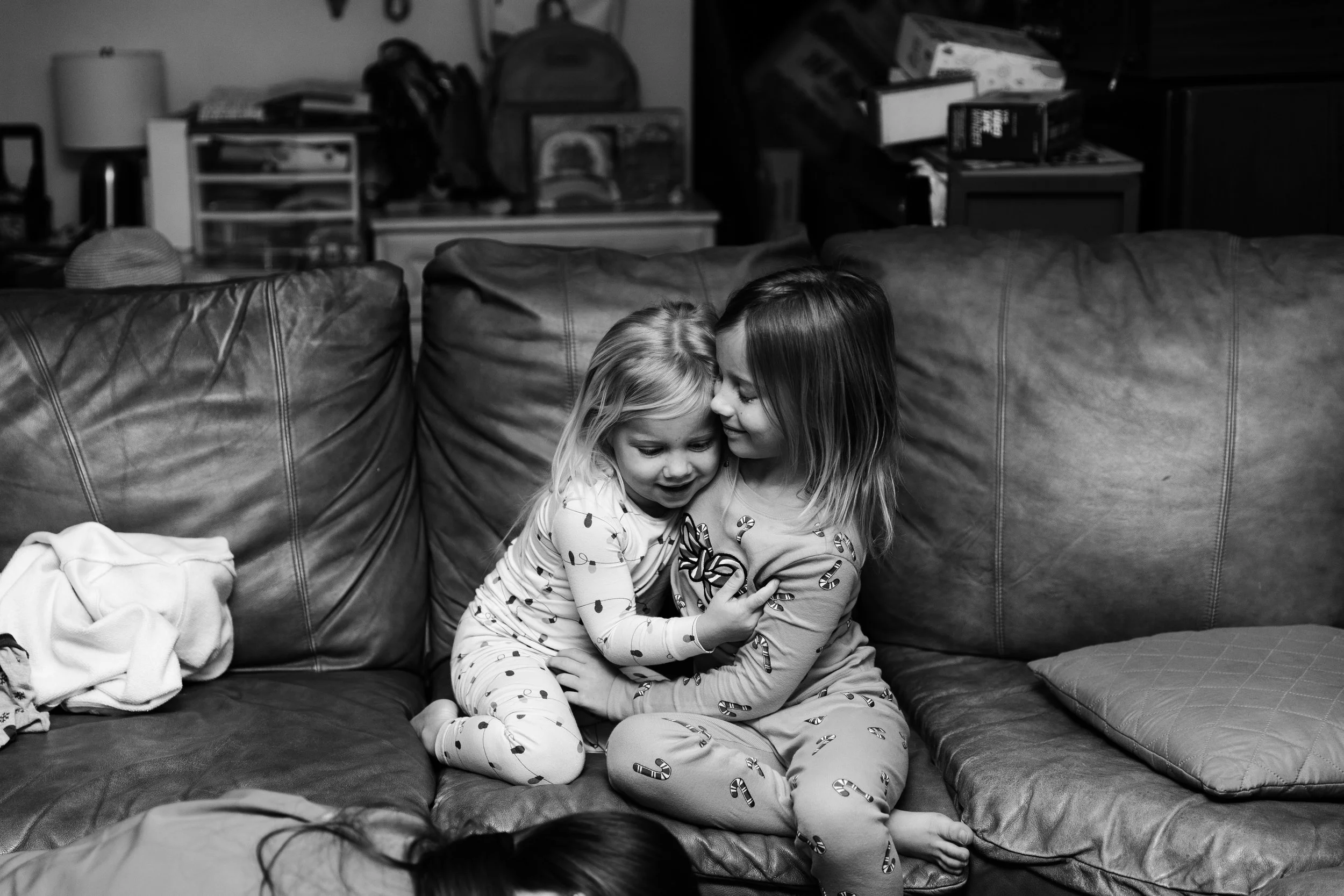 Two young girls, sisters, sit on a couch and watch the birth of their brother at home. 