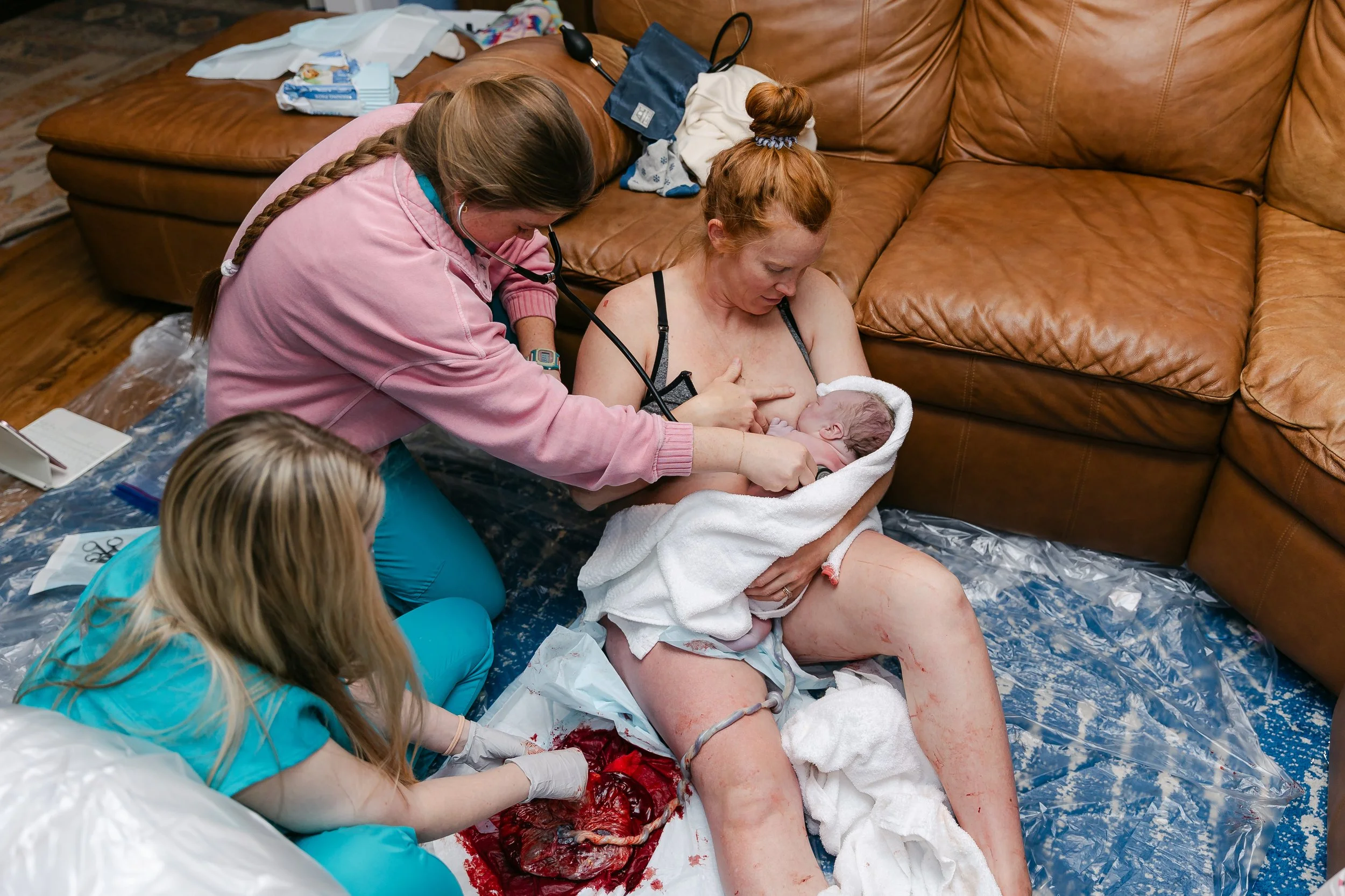 A home birth midwife team listens to a newborn and examines a placenta following a home birth in Lubbock Texas.