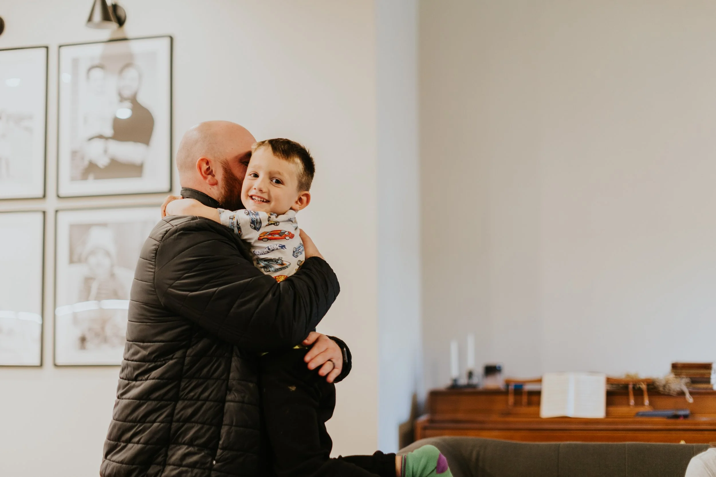 A father embraces his son while at a home prenatal visit.