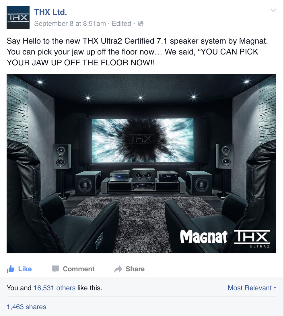 Home theater room with black leather recliners, a large screen displaying the THX logo, and multiple speakers for surround sound.