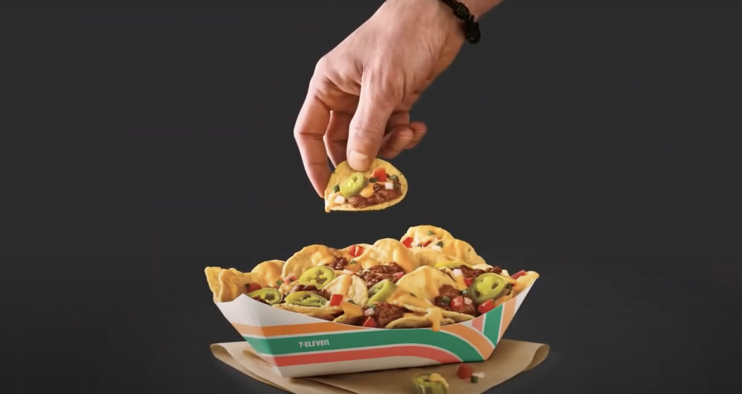A hand picks up a taco from a tray filled with various tacos.