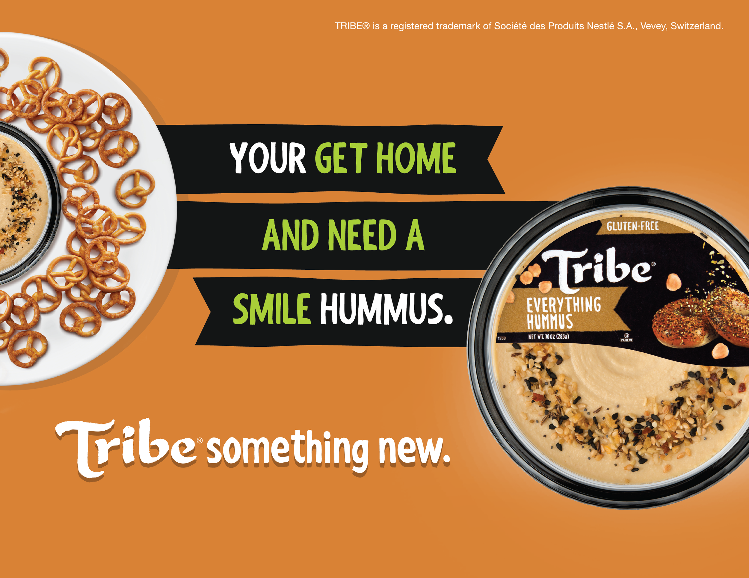 Package of Tribe Everything Hummus with sesame seeds and black cumin topping, on orange background with text encouraging people to get home and smile with hummus, and a small plate of pretzels.