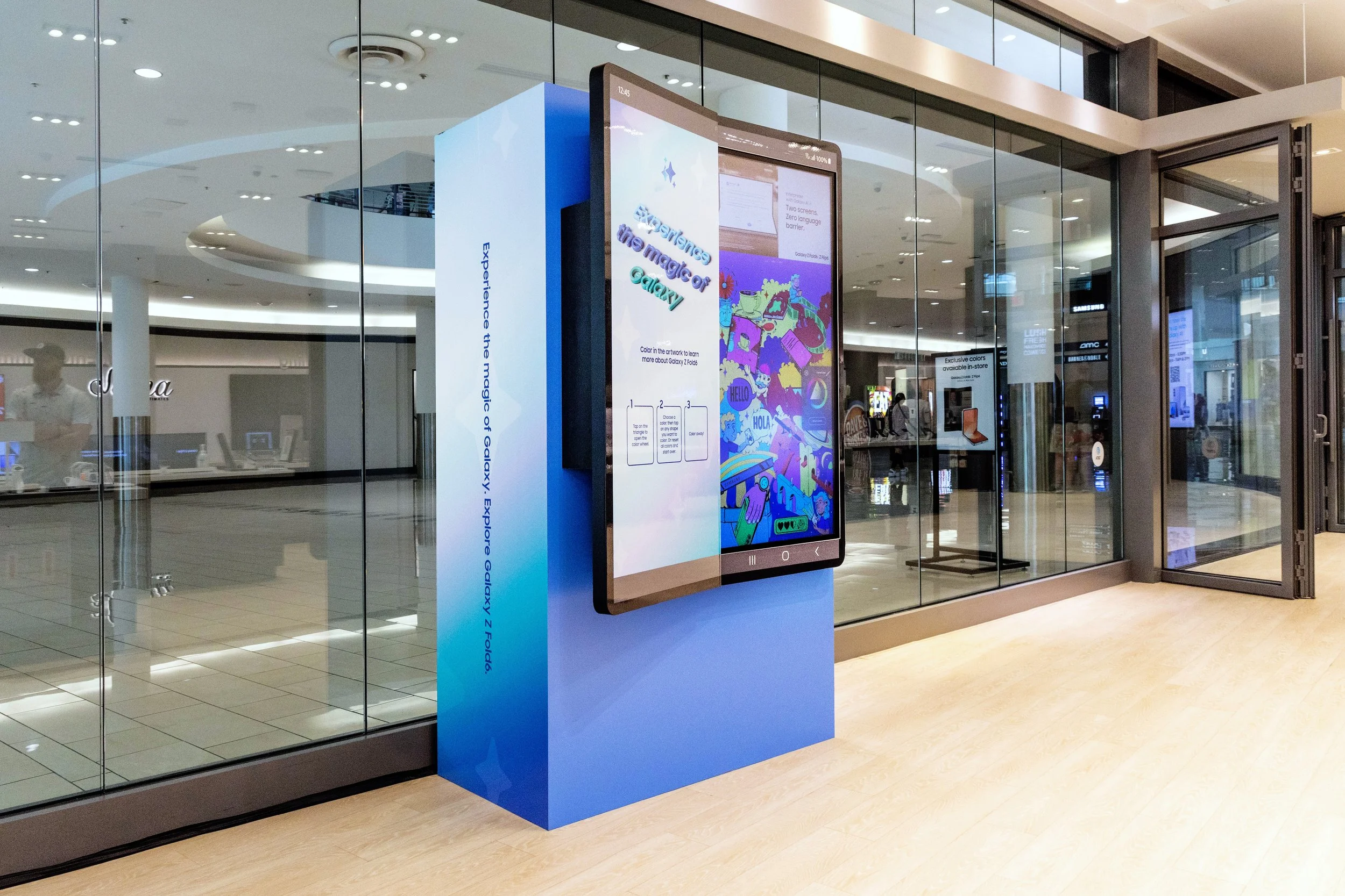 A digital display in a shopping mall promoting the Galaxy Explore Guide, featuring colorful artwork and interactive activities.