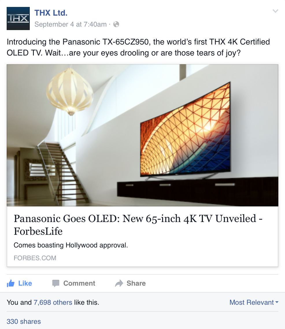 A modern living room with a staircase, a large white pendant lamp, and a mounted 65-inch 4K OLED TV displaying an abstract geometric pattern.