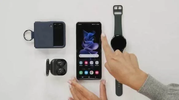 Collection of tech gadgets including a portable charger, wireless earbuds, a smartphone, and a smartwatch on a white surface.