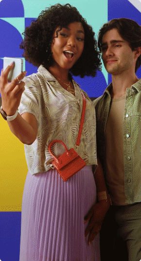 Two people taking a selfie in front of colorful geometric background