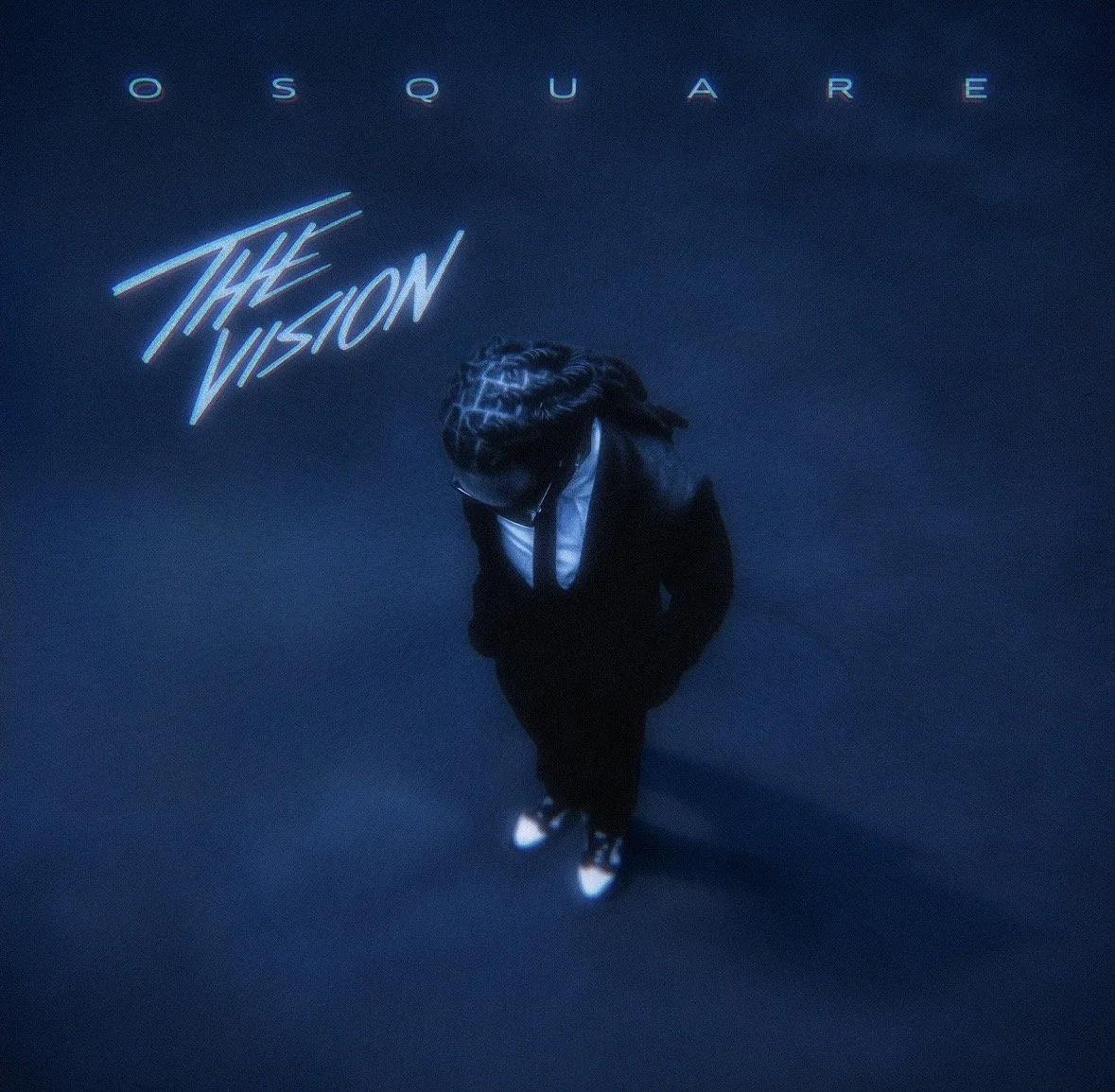 Top-down view of a person in a black suit, white shirt, and tie with braided hair and glasses, standing with hands in pockets on a dark blue background. Titles 'O S Q U A R E' and 'THE VISION' are at the top left.
