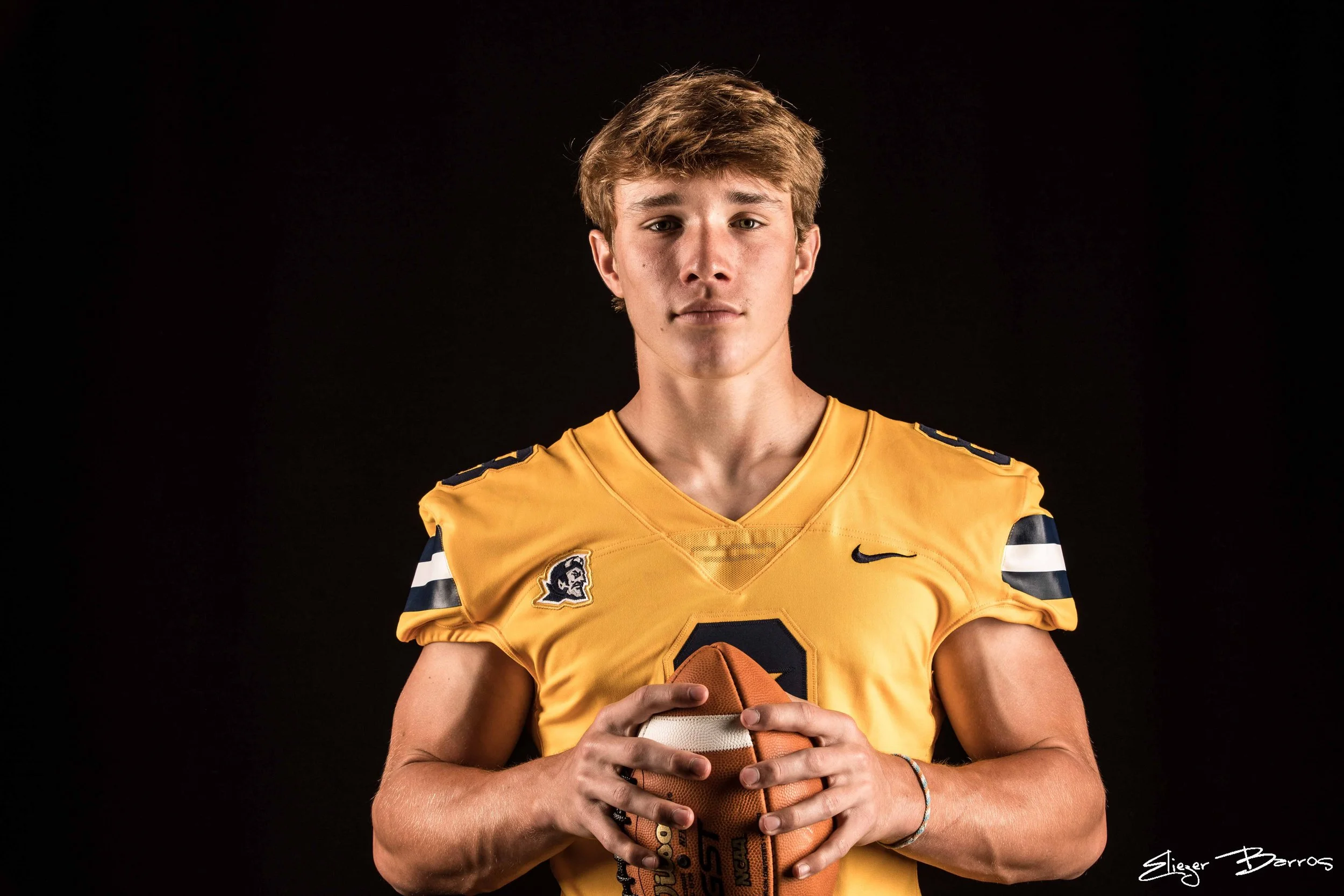 Athletic senior pictures of a football player holding a ball in Pittsburgh studio