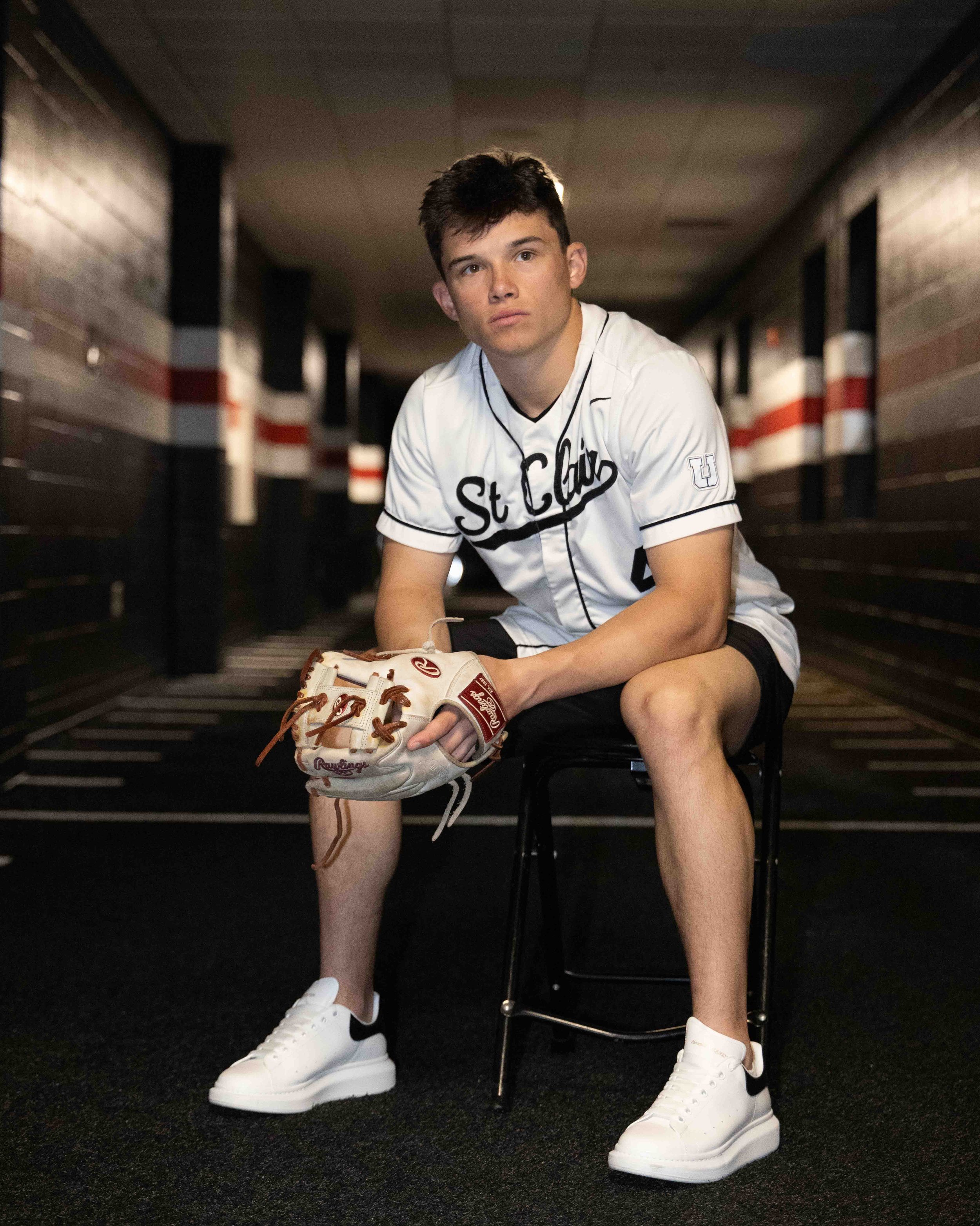 Class of 2026 Upper St. Clair senior Nico in baseball uniform sitting with glove during his senior pictures