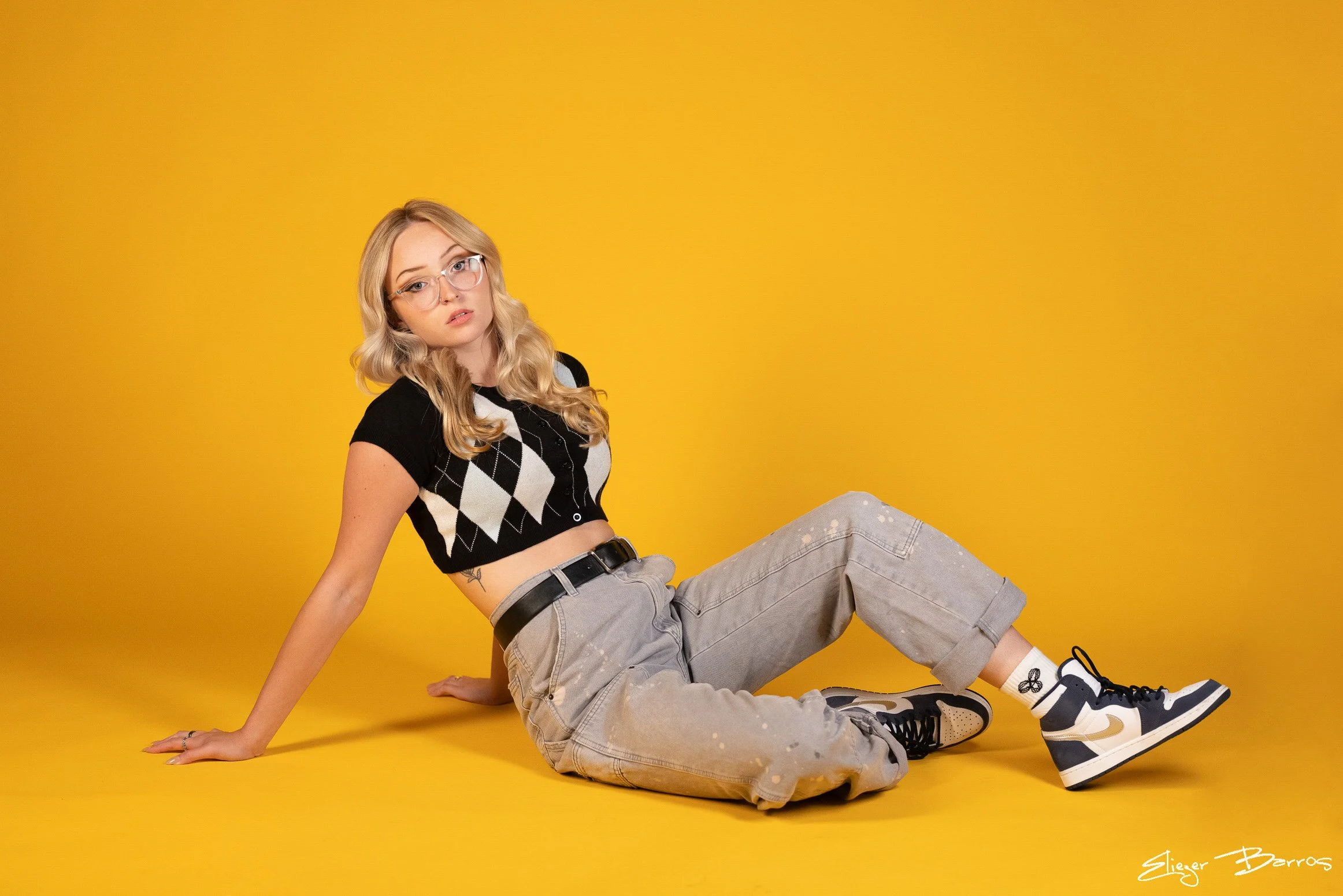 Fun senior pictures of a young woman in stylish outfit on yellow background in Pittsburgh studio