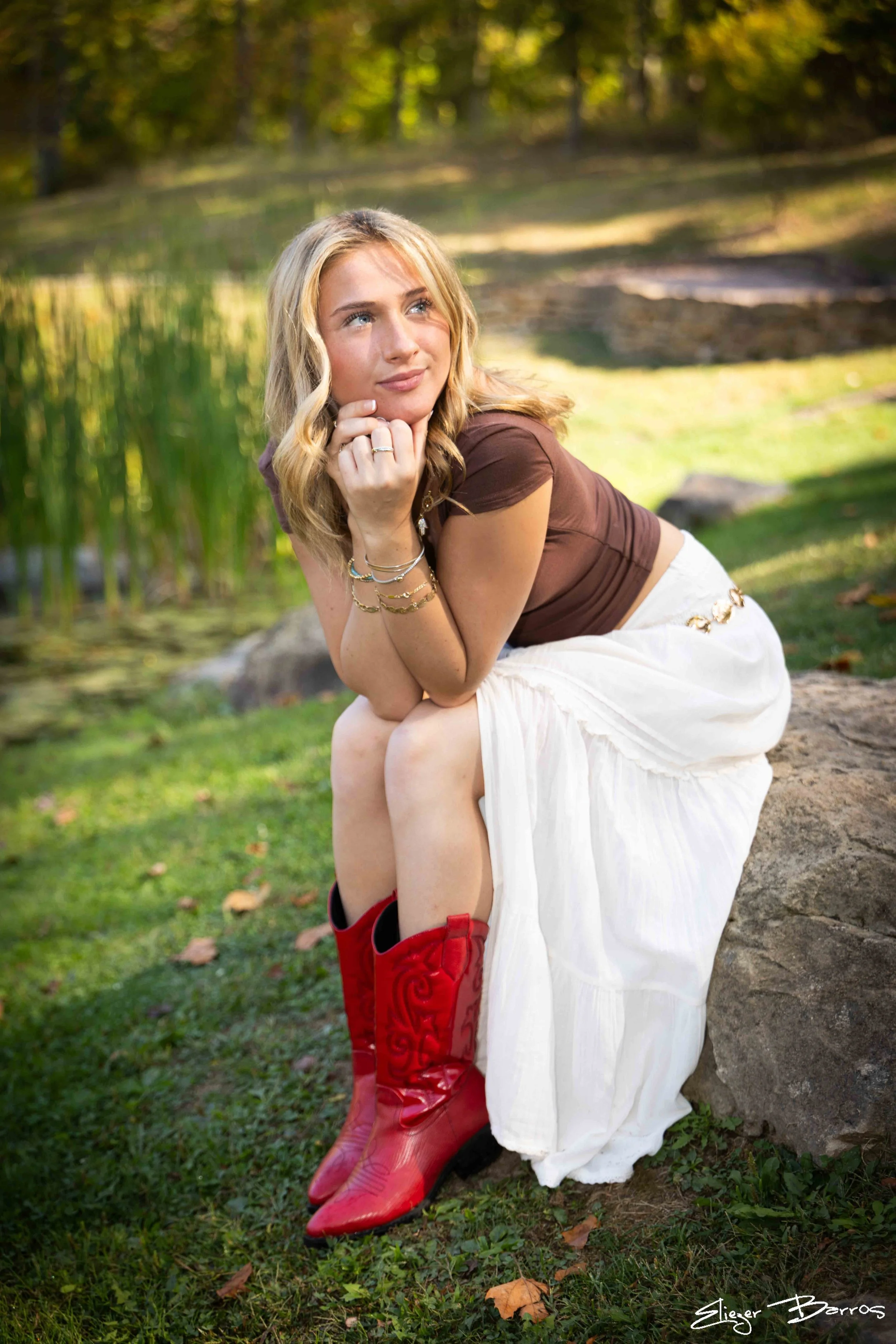 Mt. Lebanon senior Kate sitting by the water wearing red boots at Pittsburgh Botanic Garden