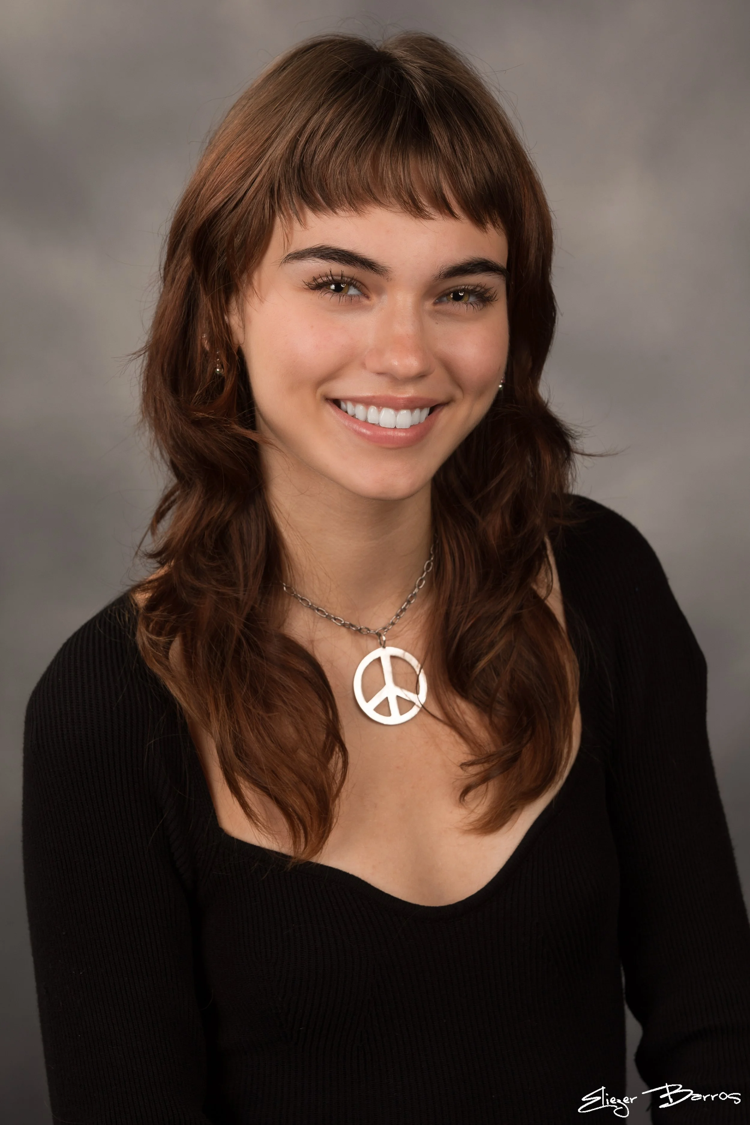 Studio senior pictures of a smiling young woman with peace sign necklace in Pittsburgh