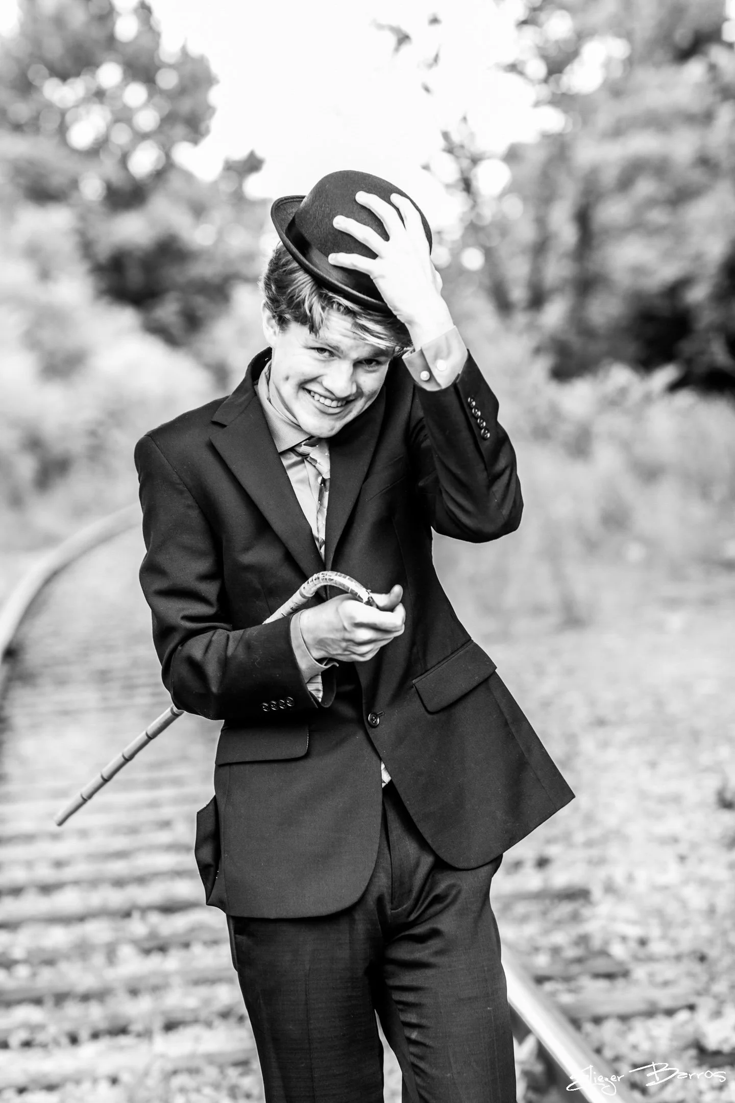 Creative black and white senior pictures of a young man in suit and hat on railroad tracks Pittsburgh