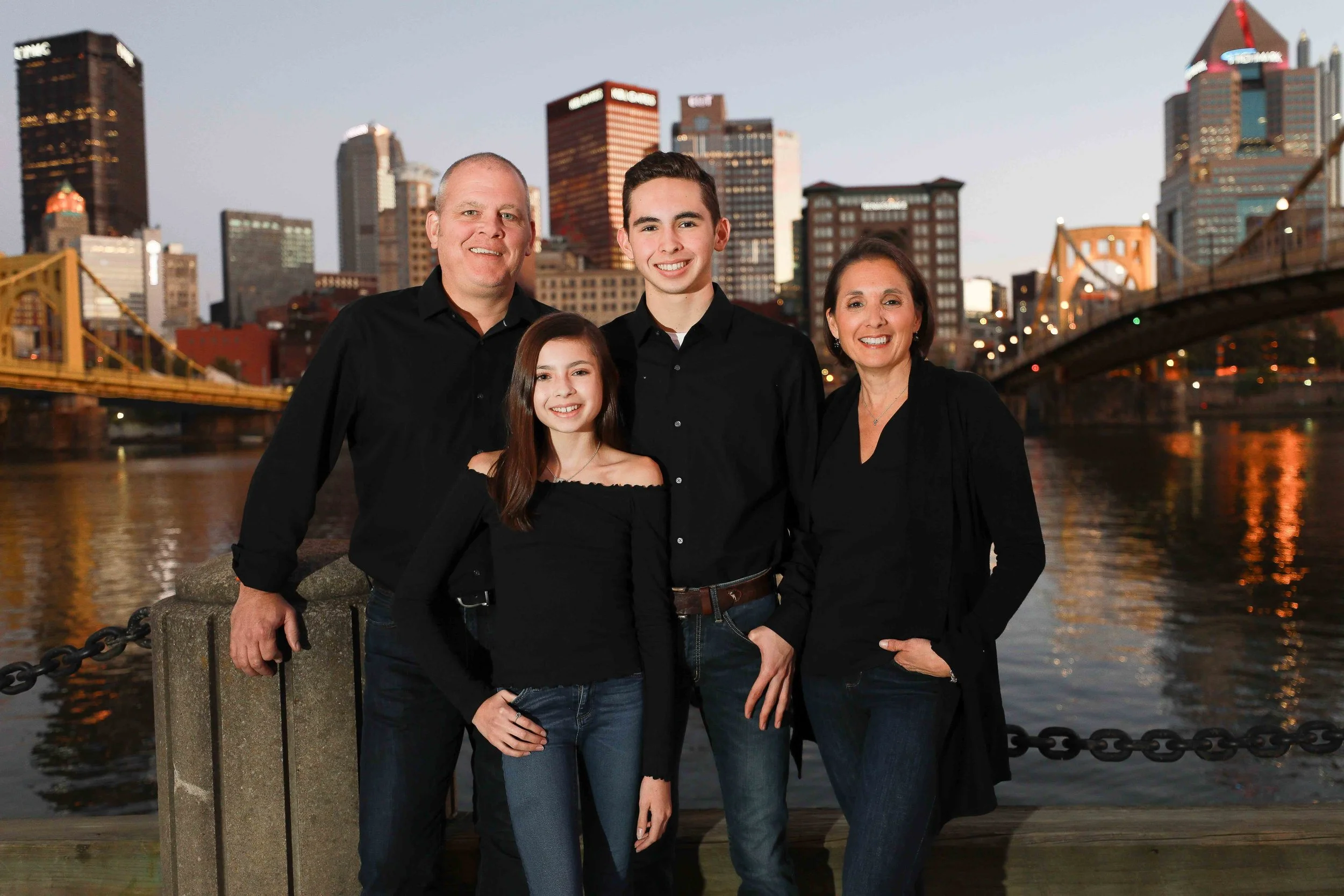 Family portraits by the river with Pittsburgh skyline background