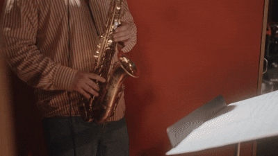 Person playing a saxophone in a room with orange walls