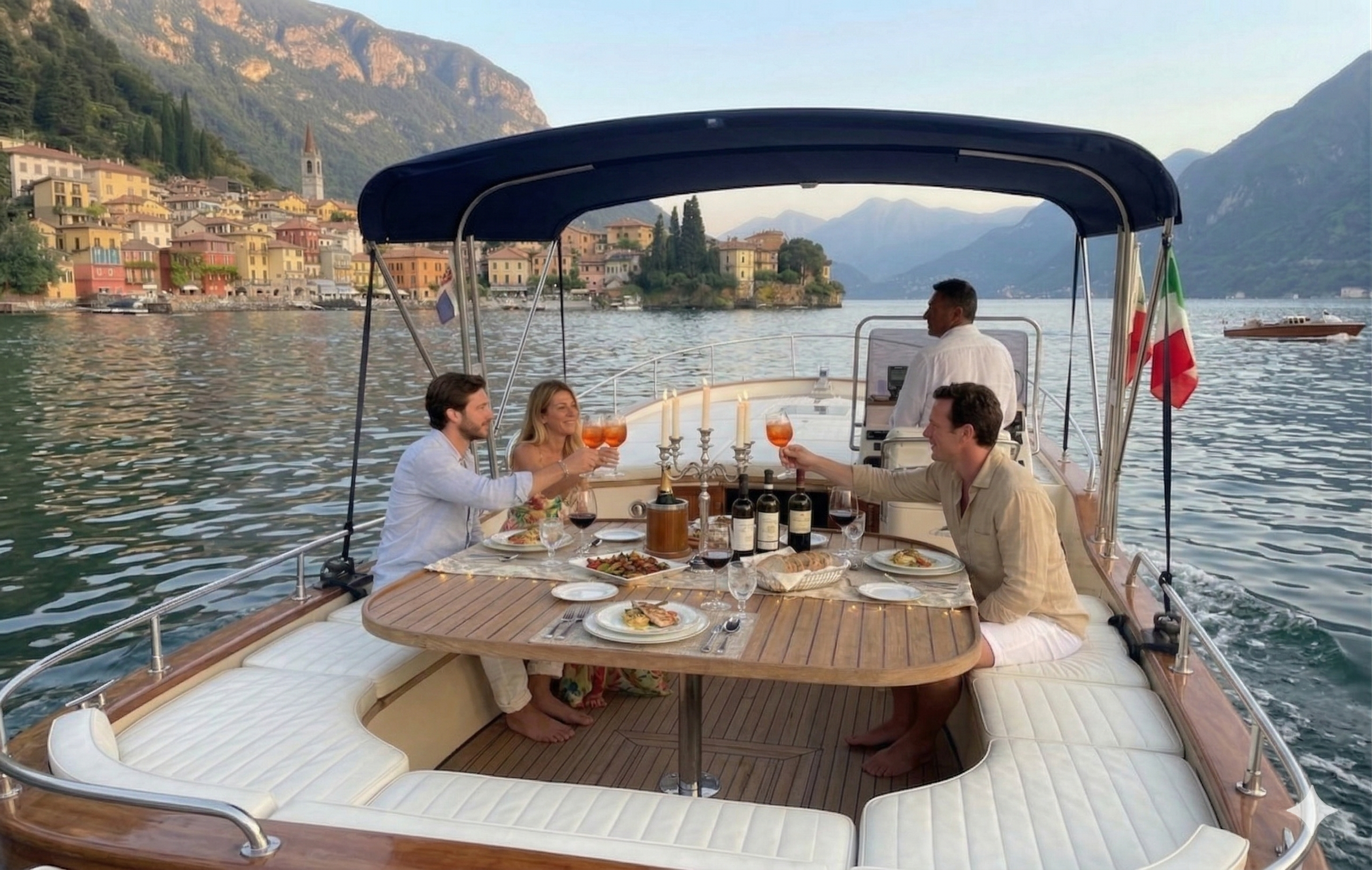 Three people enjoying an outdoor meal on a boat with picturesque lakeside town and mountains in the background.