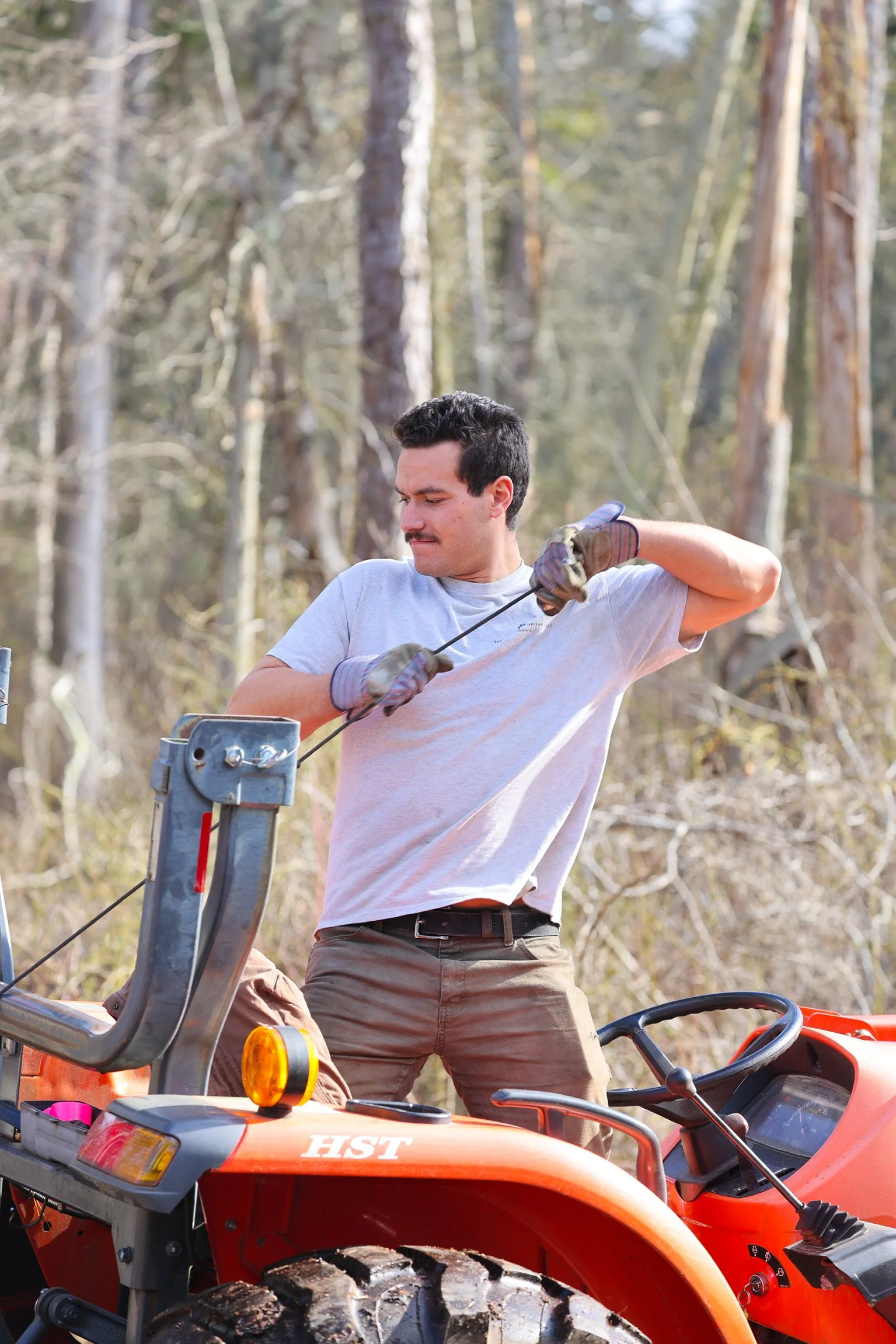 Man operating a tractor in a forested area.