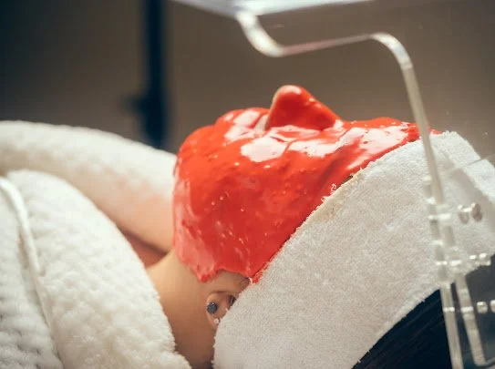 Client with a red Goji facial mask applied to the face.