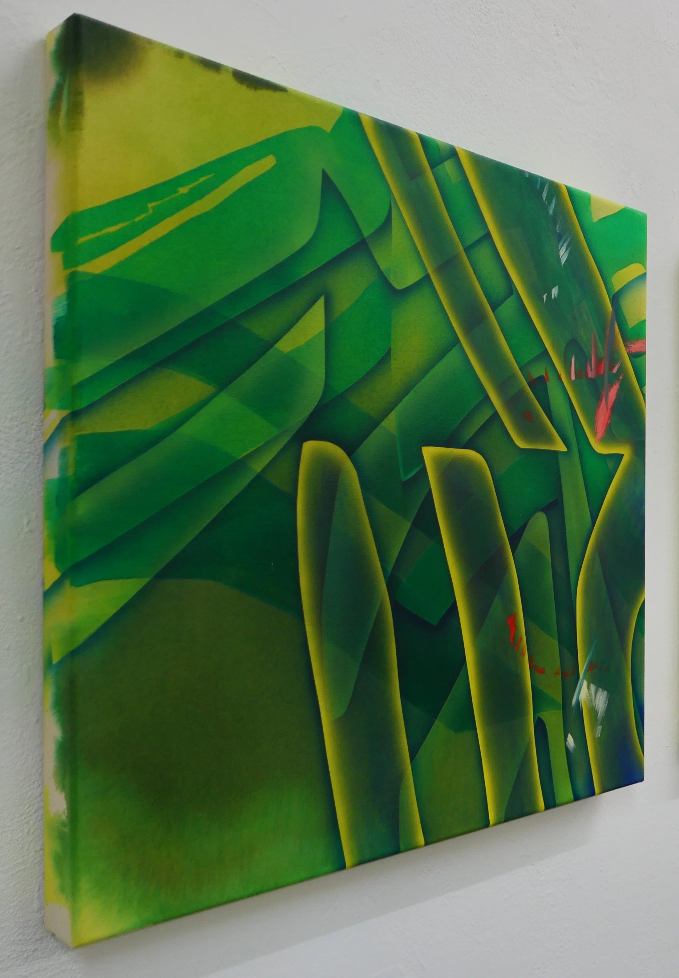 Close-up view of abstract green and yellow painted canvas artwork hanging on a white wall.