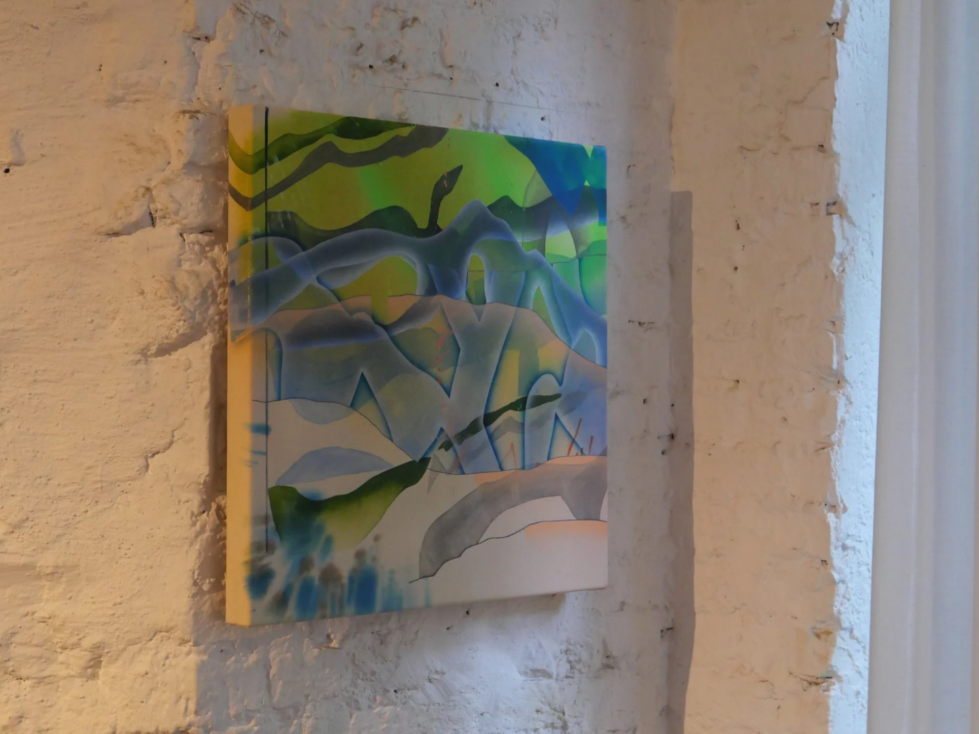 An abstract colorful painting on a rectangular canvas hanging on a textured white brick wall.