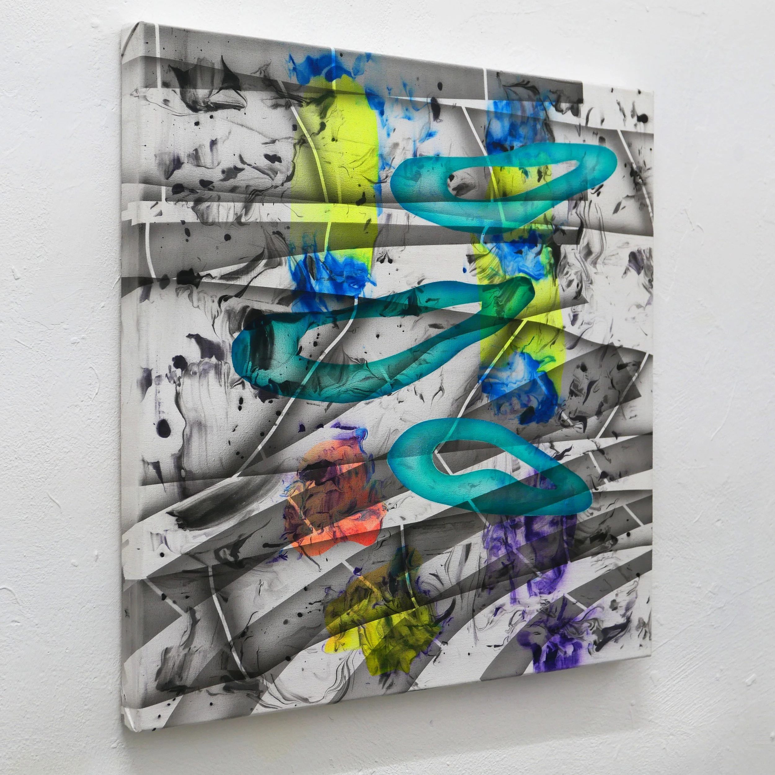 Mixed media abstract artwork with black, yellow, blue, purple, and orange paint splatters and swirling lines on a white canvas, mounted on a white wall.
