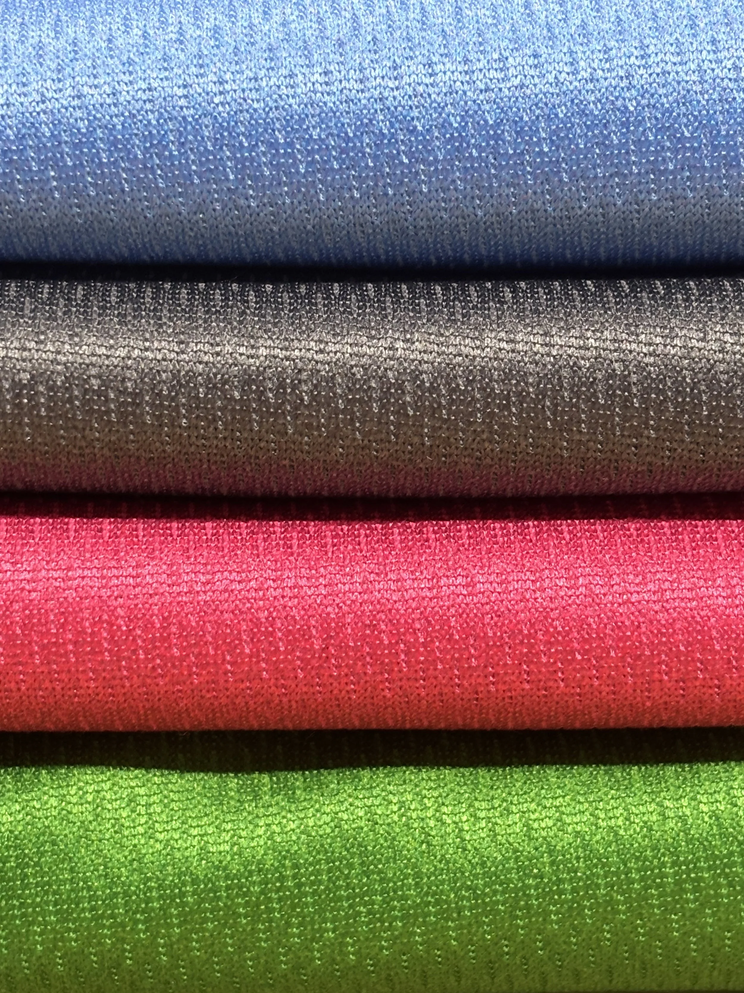 Stacked fabric rolls in blue, black, red, and green colors.