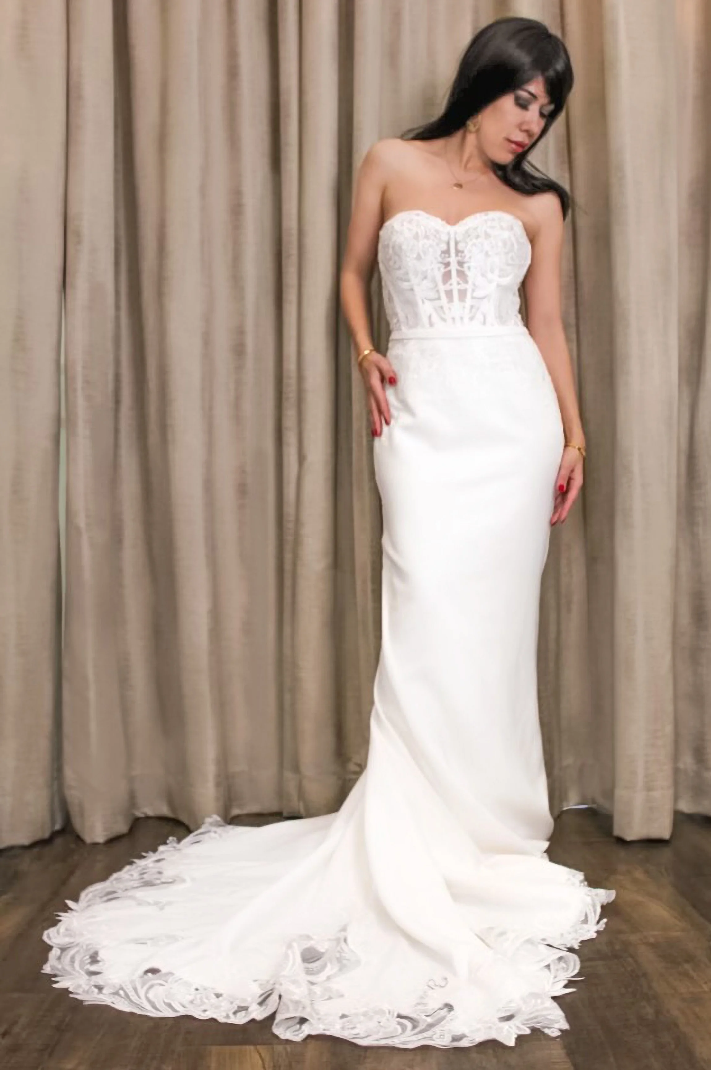 Strapless sheath wedding dress. Fitted corset bodice with exposed boning and a straight neckline. Slim skirt that skims the body with a small sweep train. Made from lace bodice and smooth crepe skirt. Clean modern bridal style.