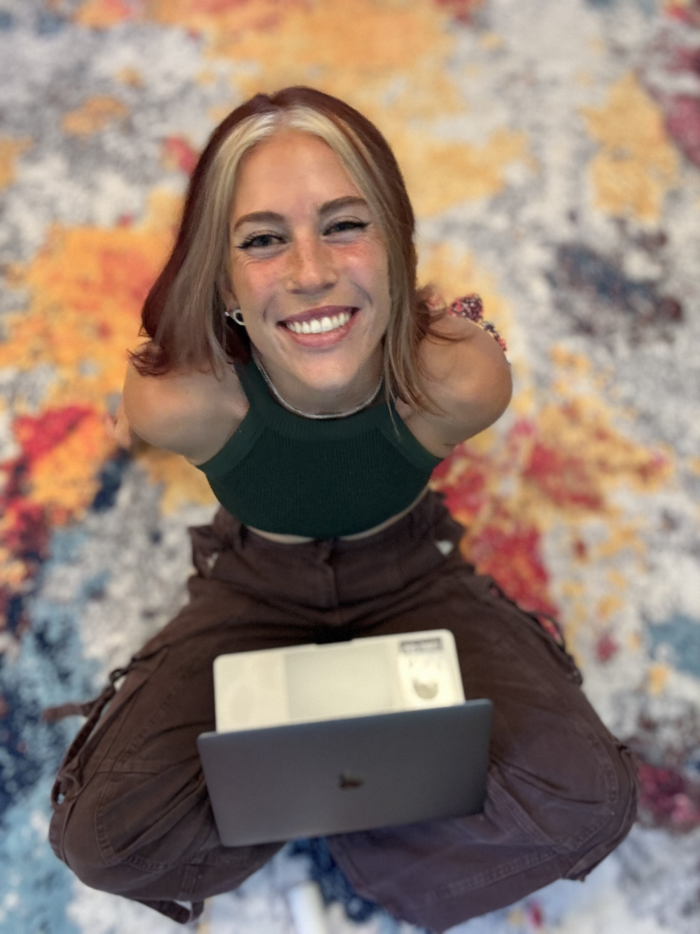 Girl in green shirt smiling with a laptop on her lap