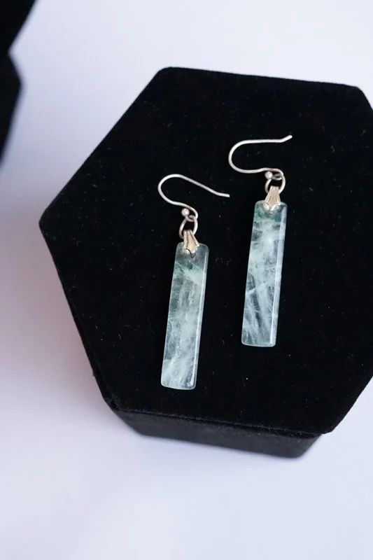 Pair of rectangular jade earrings with hooks, resting on a black velvet surface.