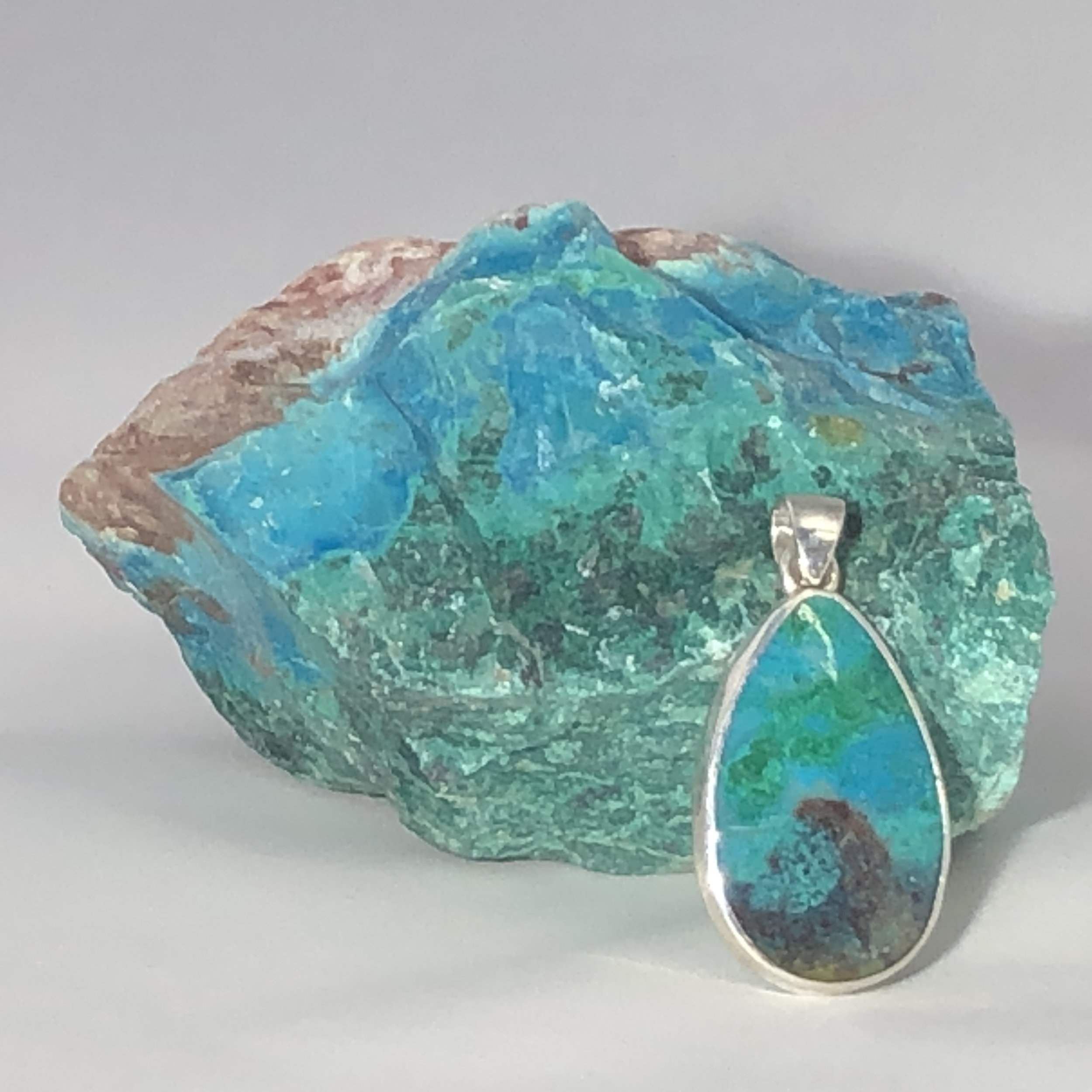 A ring with a large, triangular, greenish-blue aquamarine gemstone set in a silver or white gold band, with smaller diamonds accenting the band.